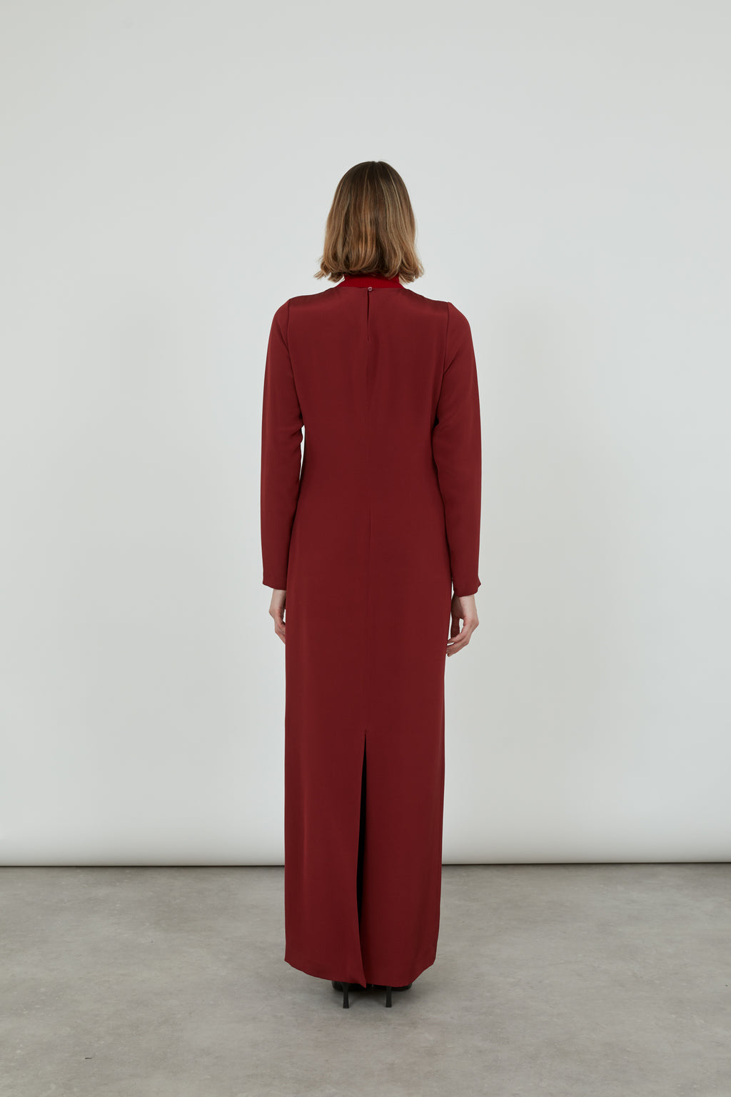 Woman wearing a long red Abelun dress in silk, showing the back of the dress.
