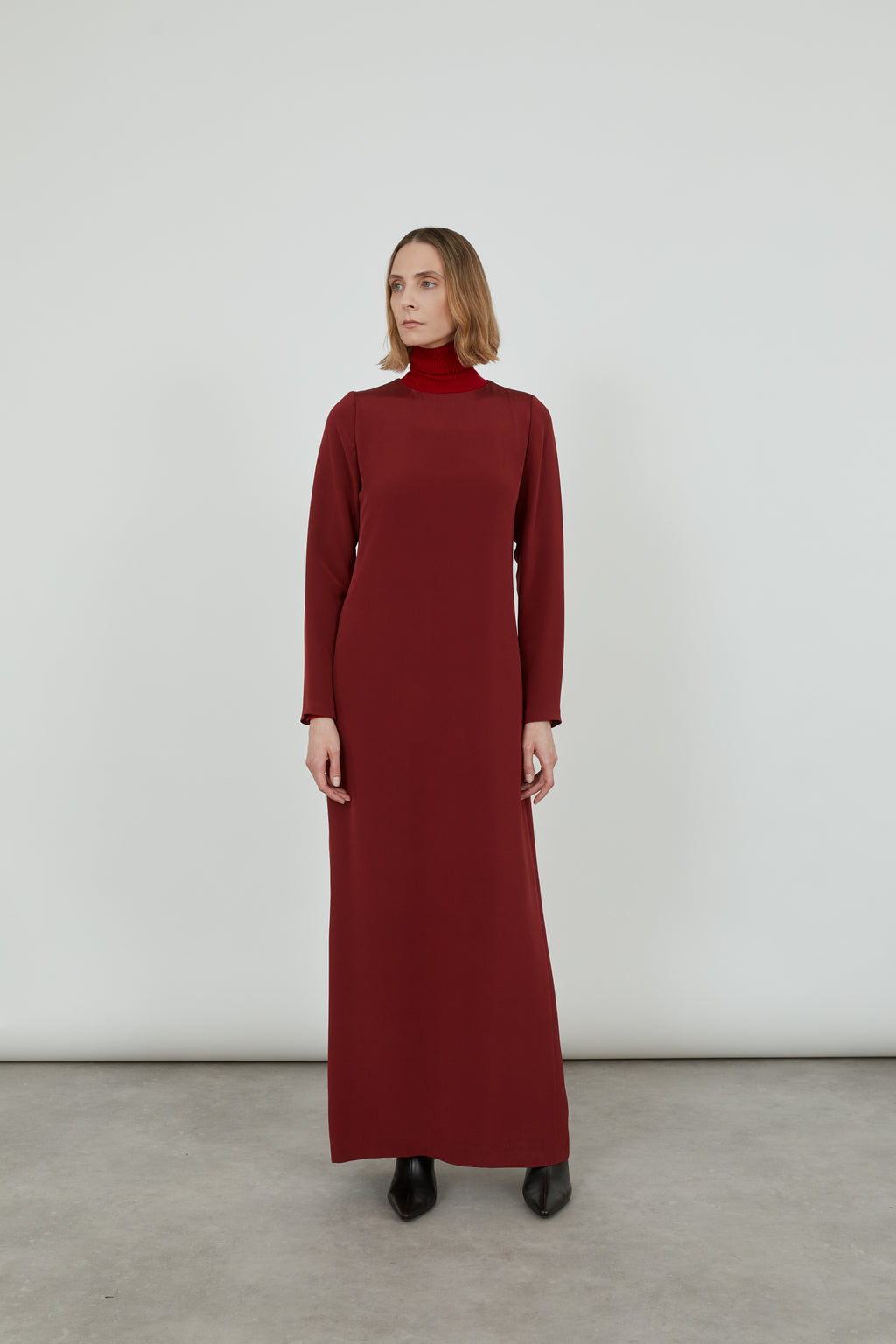 Woman wearing a maxi red Abelun dress in crepe silk and looking at the right.