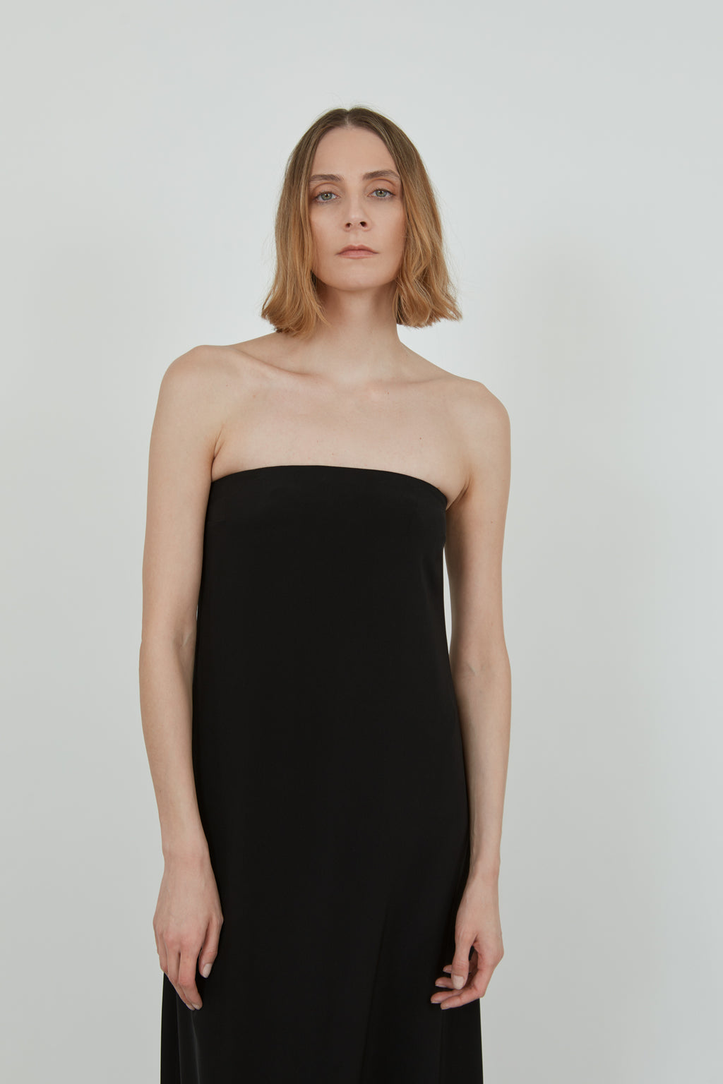 Detailed view of a woman wearing a black strapless dress.