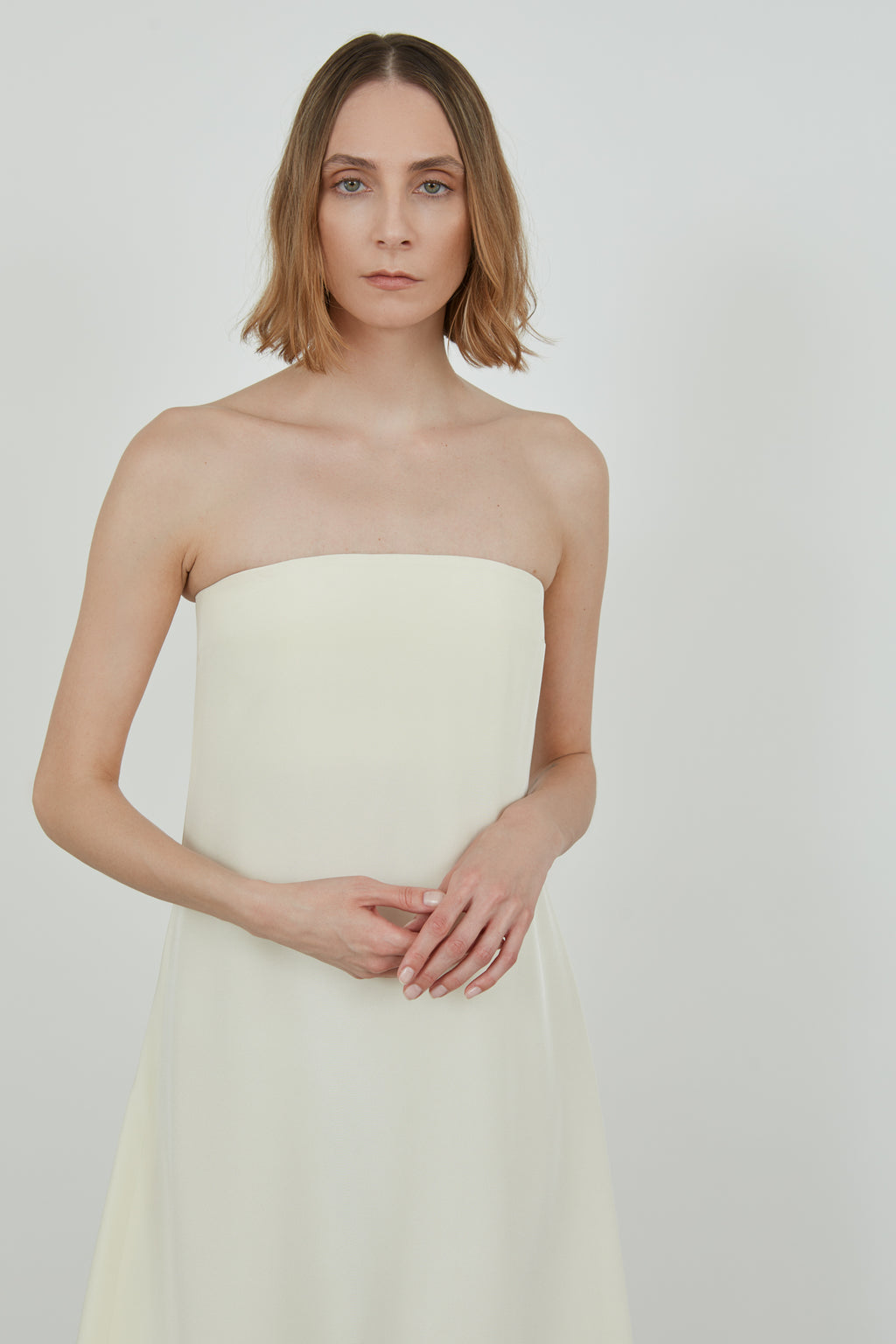Detailed view of a woman wearing an off hite strapless dress.