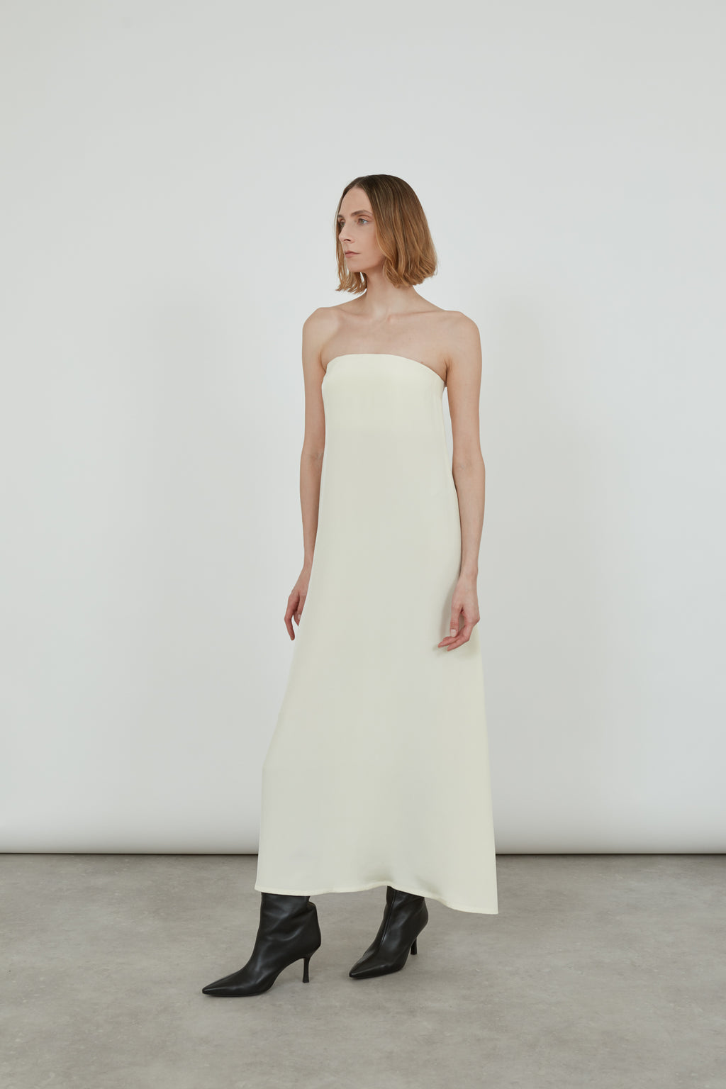 Woman wearing a cream bandeau dress looking sideways.