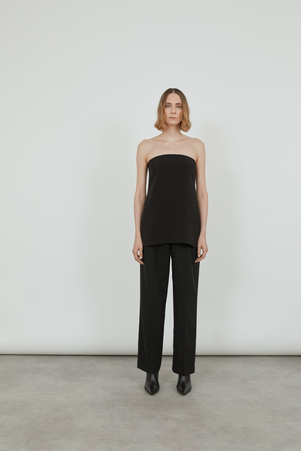 Woman wearing a black strapless bandeau top with a black trousers.