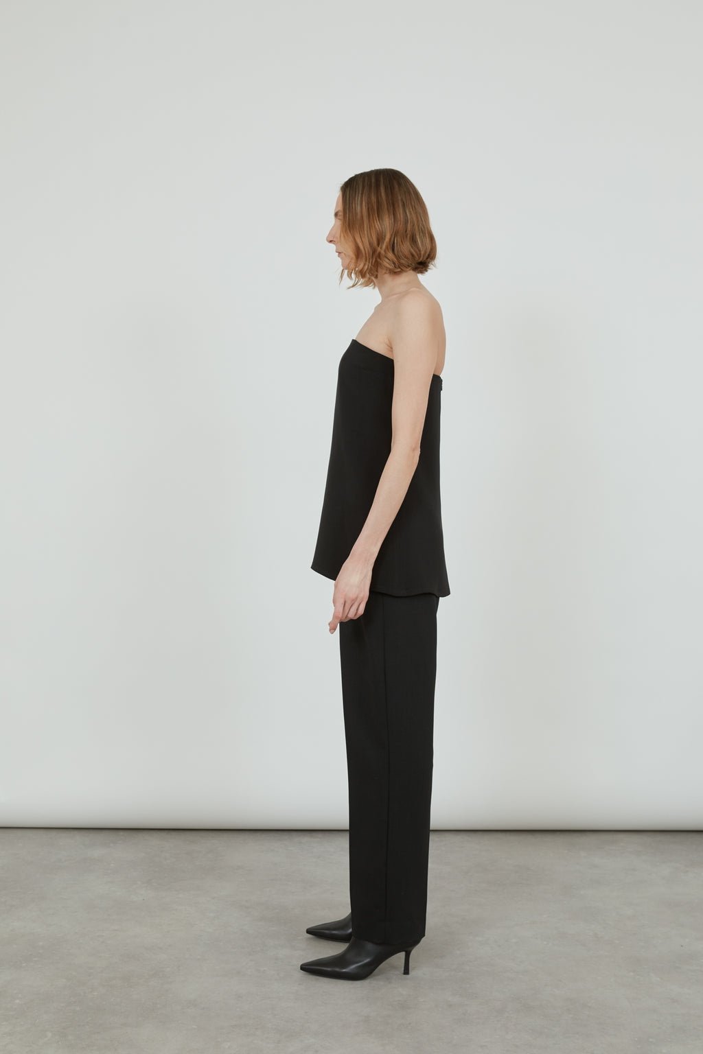 Woman wearing a black bandeau top looking at the right side.