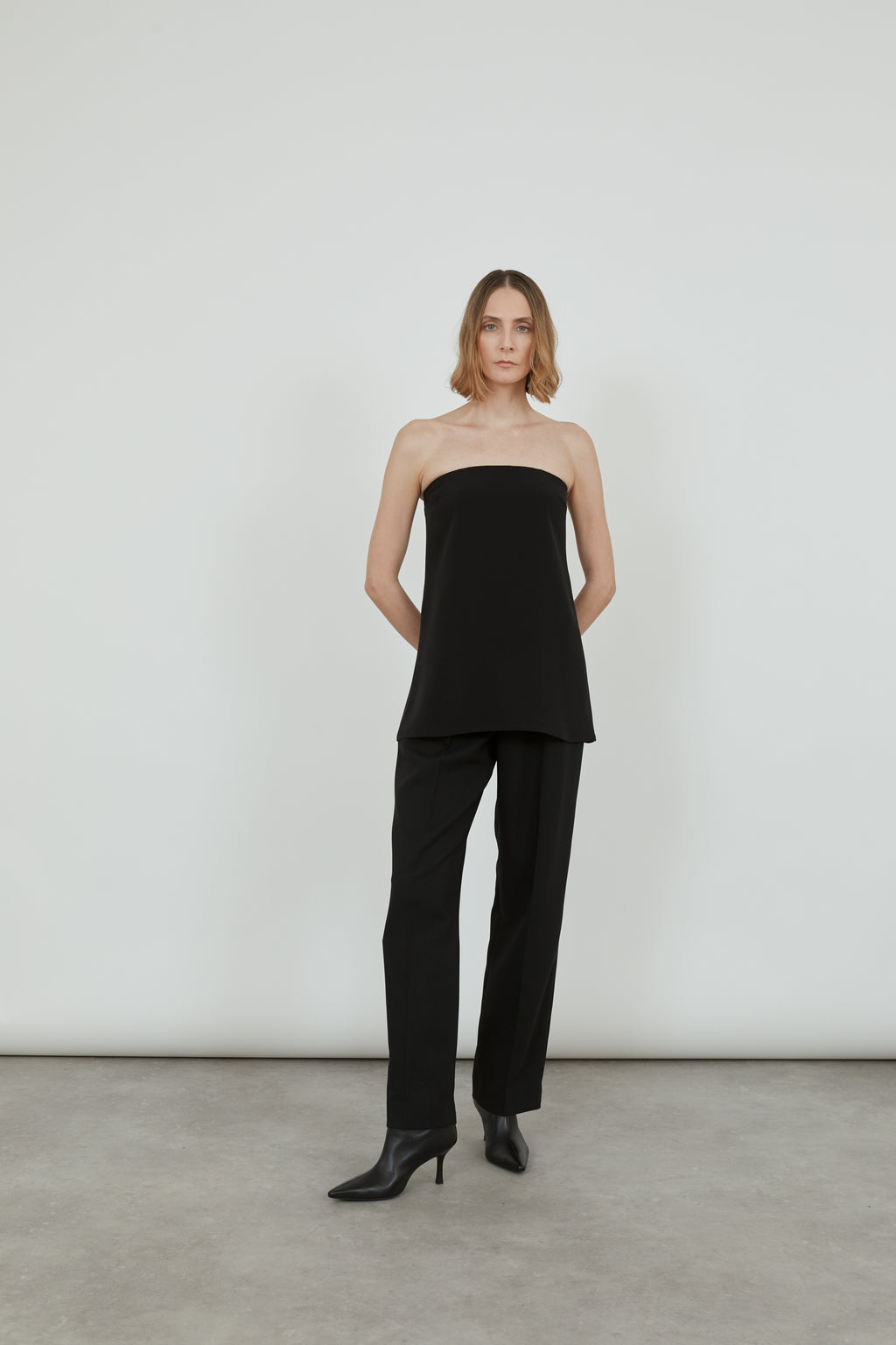 Woman wearing black strapless top with black pants.