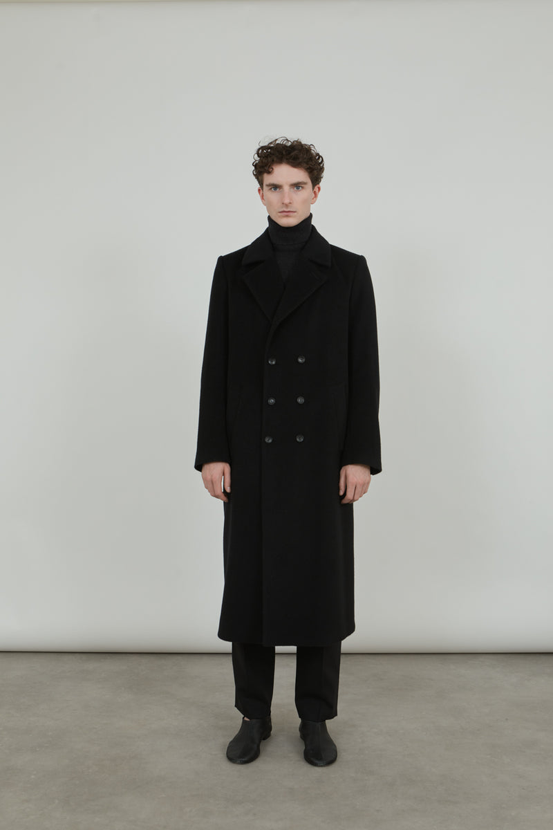 Person wearing a black Achilles coat in cashmere wool.