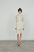 a full cream outfit, wool silk shirt and wool shorts with black leather sandals. 
