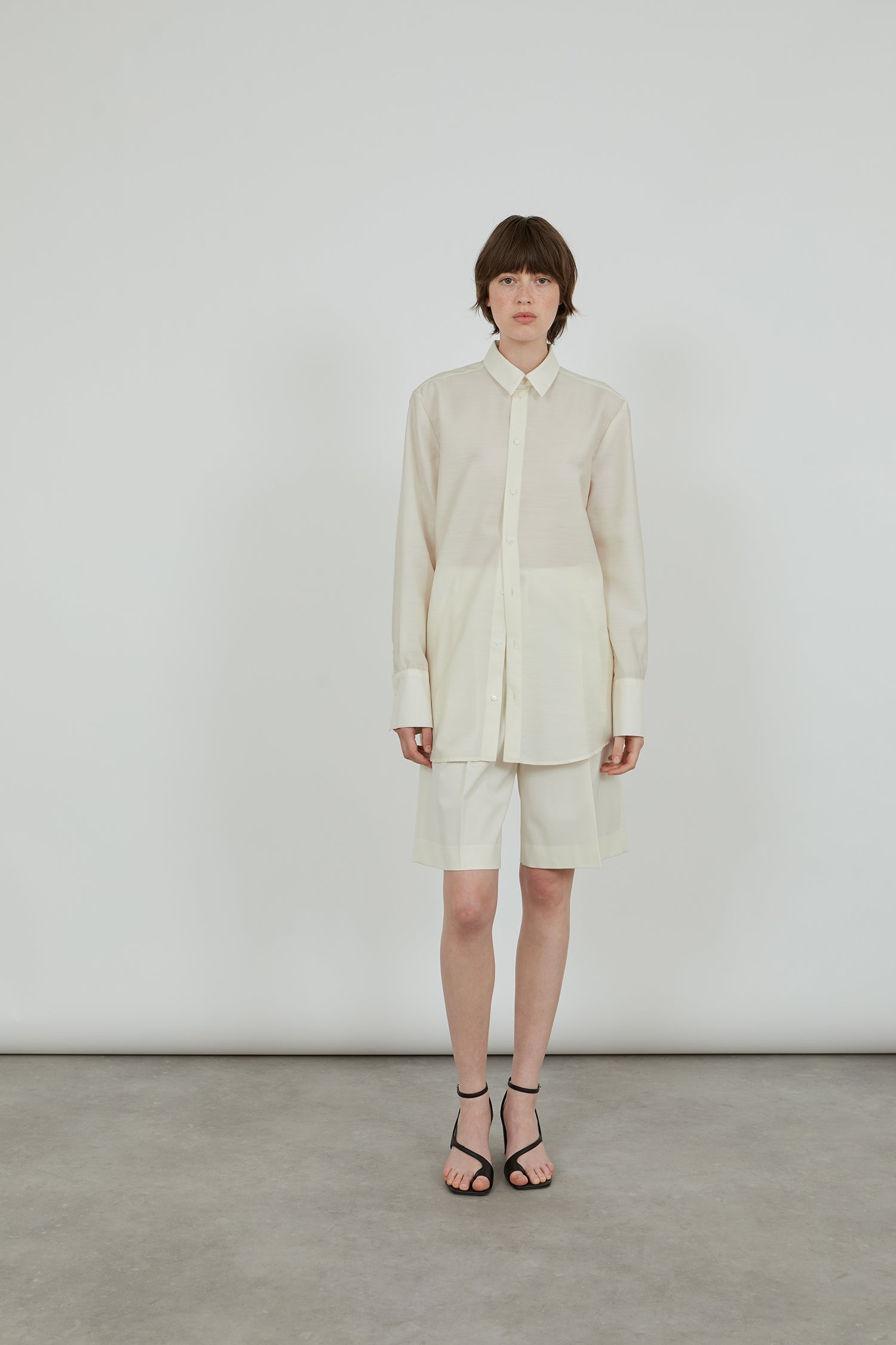 a full cream outfit, wool silk shirt and wool shorts with black leather sandals. 