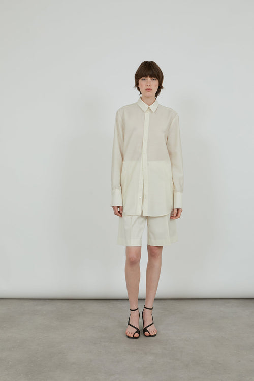 a full cream outfit, wool silk shirt and wool shorts with black leather sandals. 