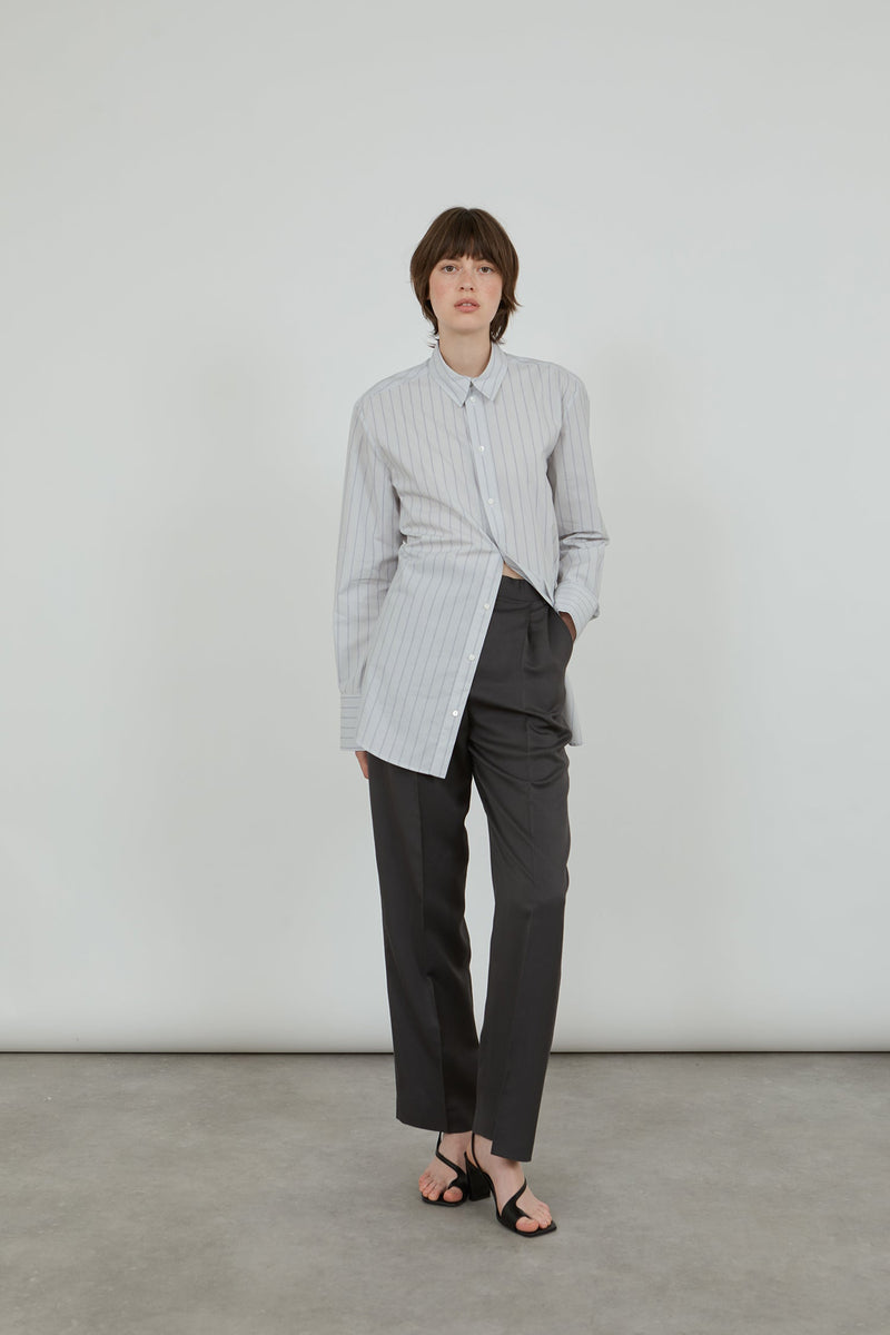 Woman wearing a classic striped men's shirt with tailored trousers. 