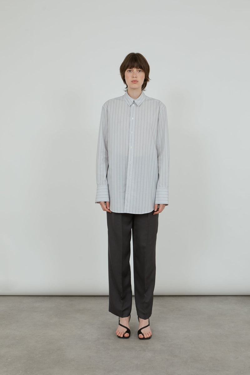 Woman wearing a classic striped men's shirt with tailored grey pants.