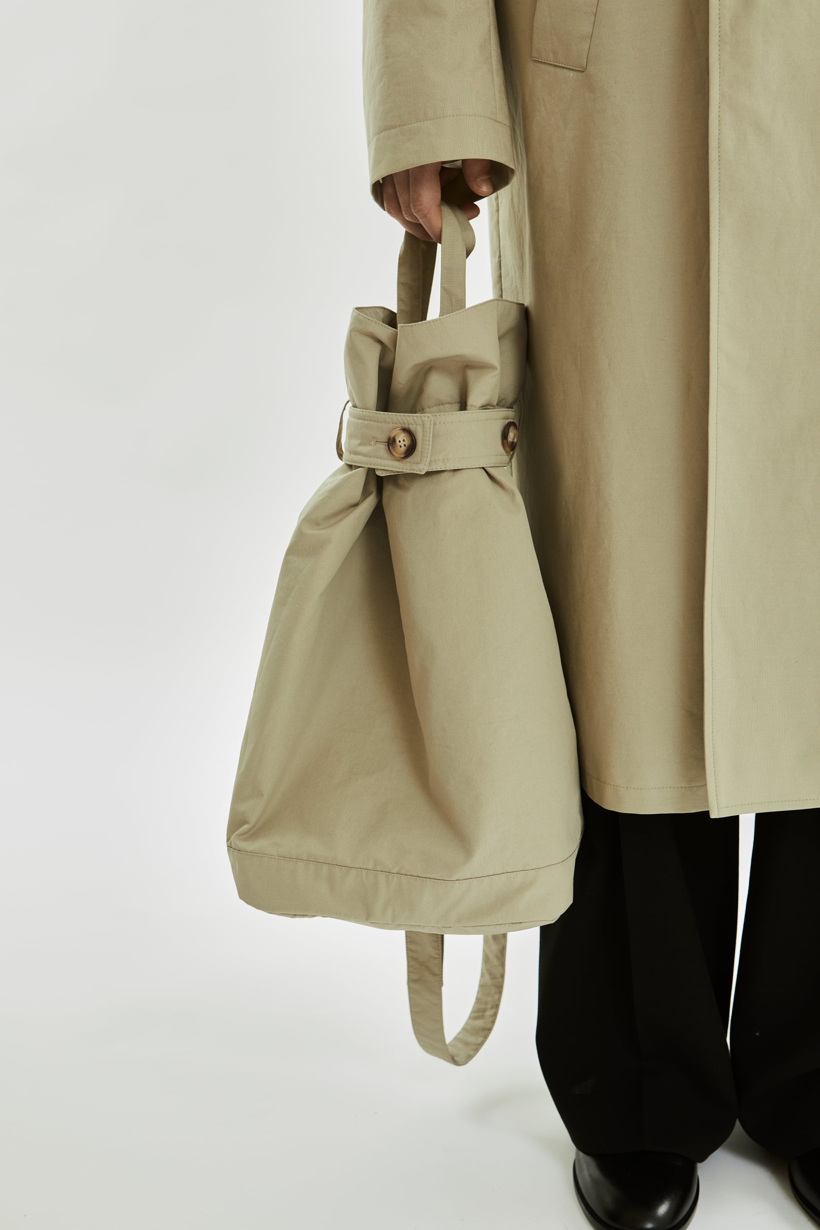 Person holding a beige tote bag with a plain background
