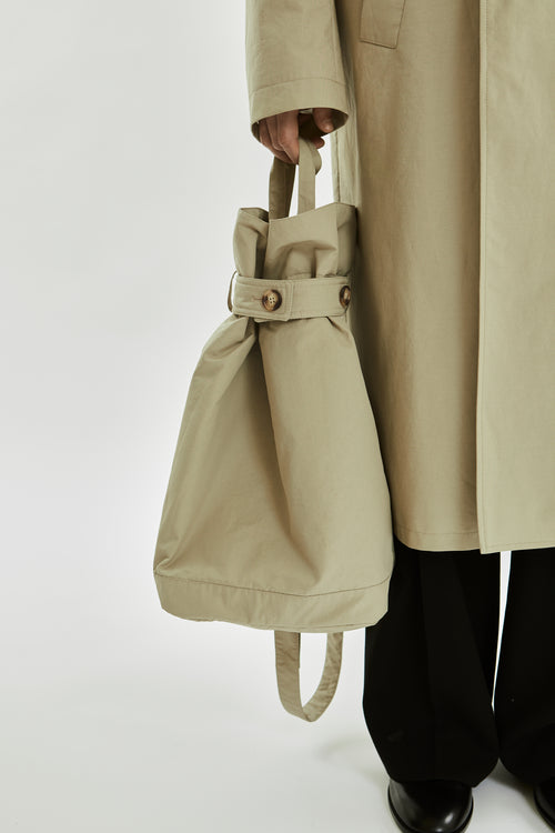 Person holding a beige tote bag with a plain background