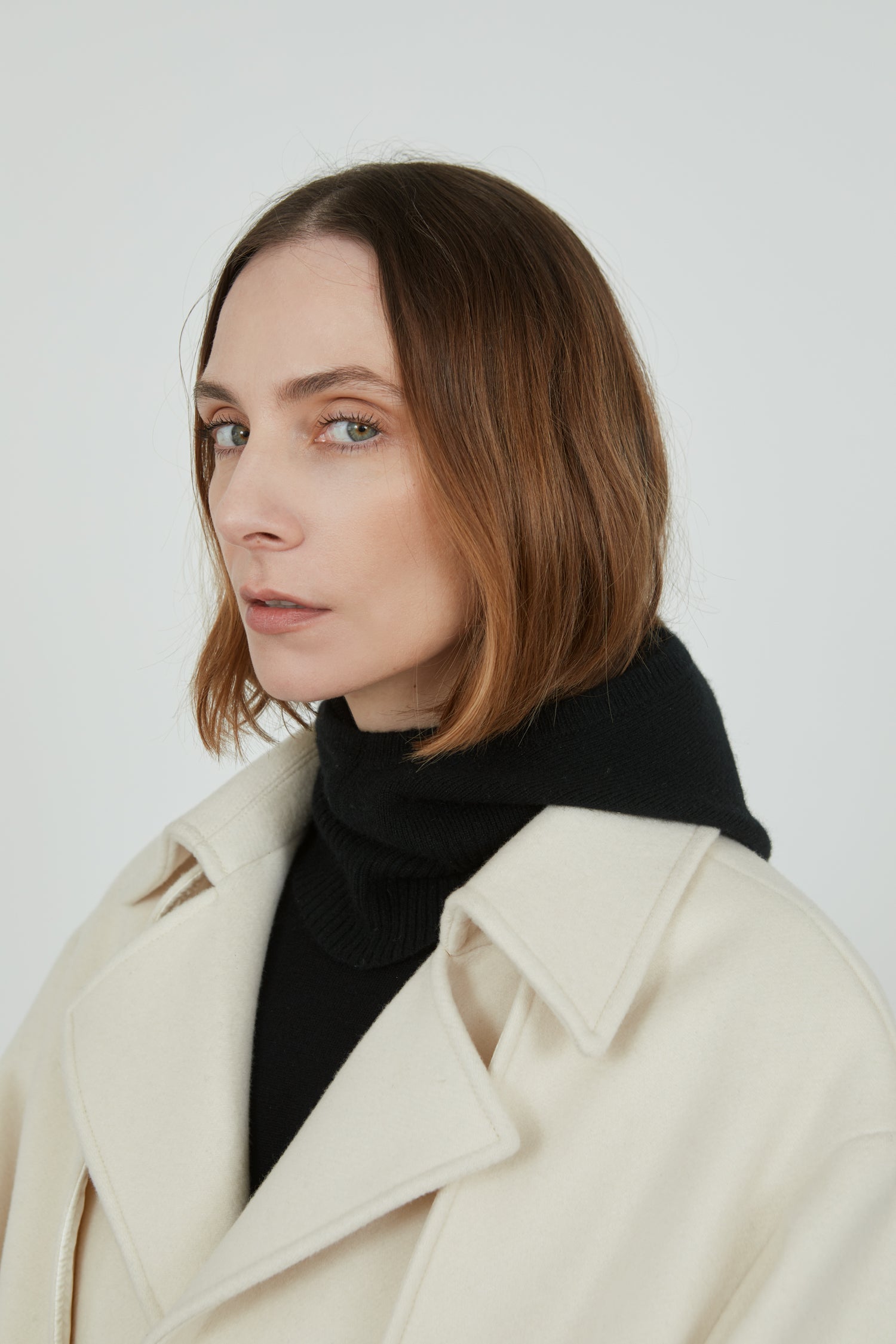 Black Cathy balaclava in merino wool combined with an offwhite cashmere coat, hood off