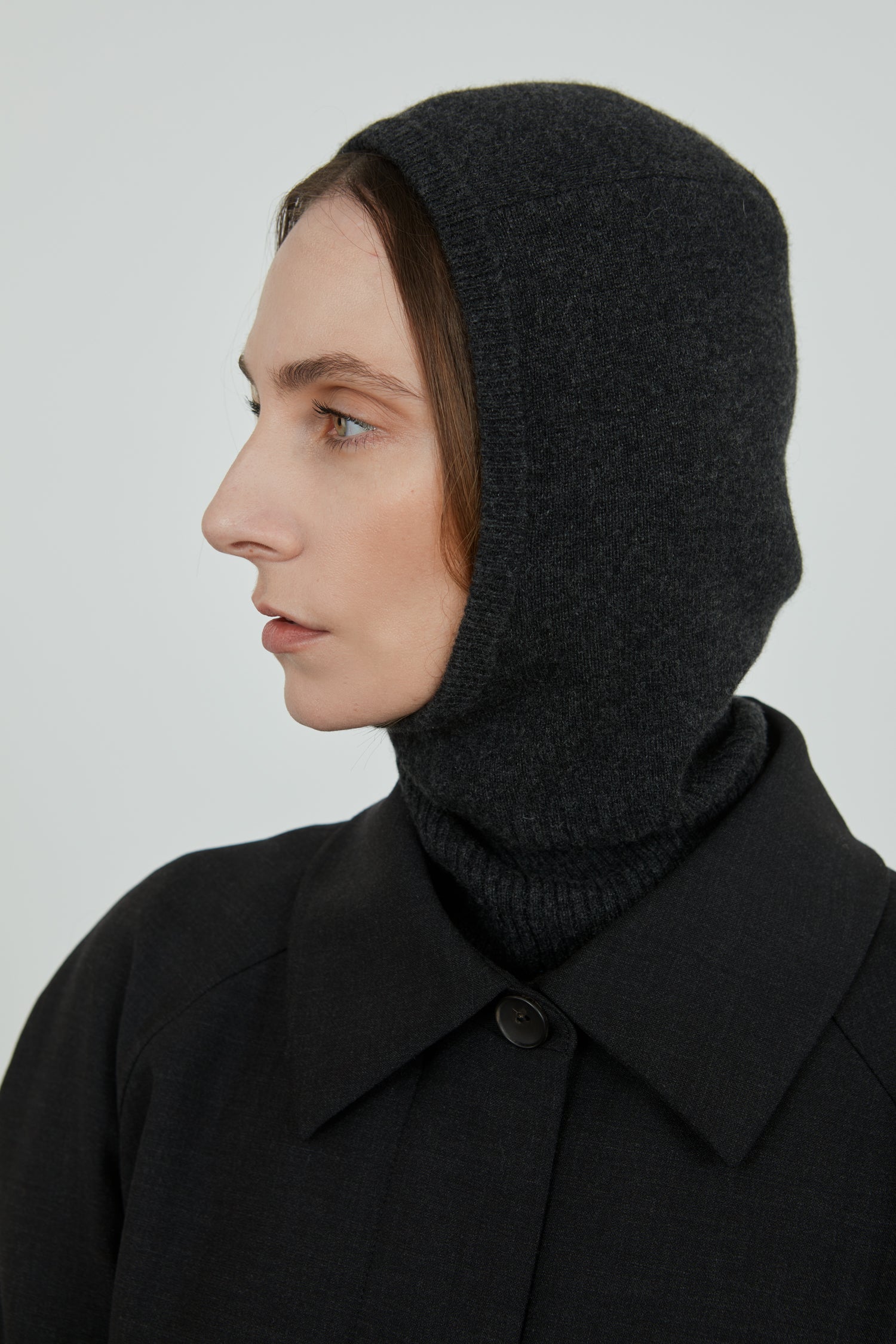 Dark grey Cathy balaclava in merino wool combined with a dark grey coat.