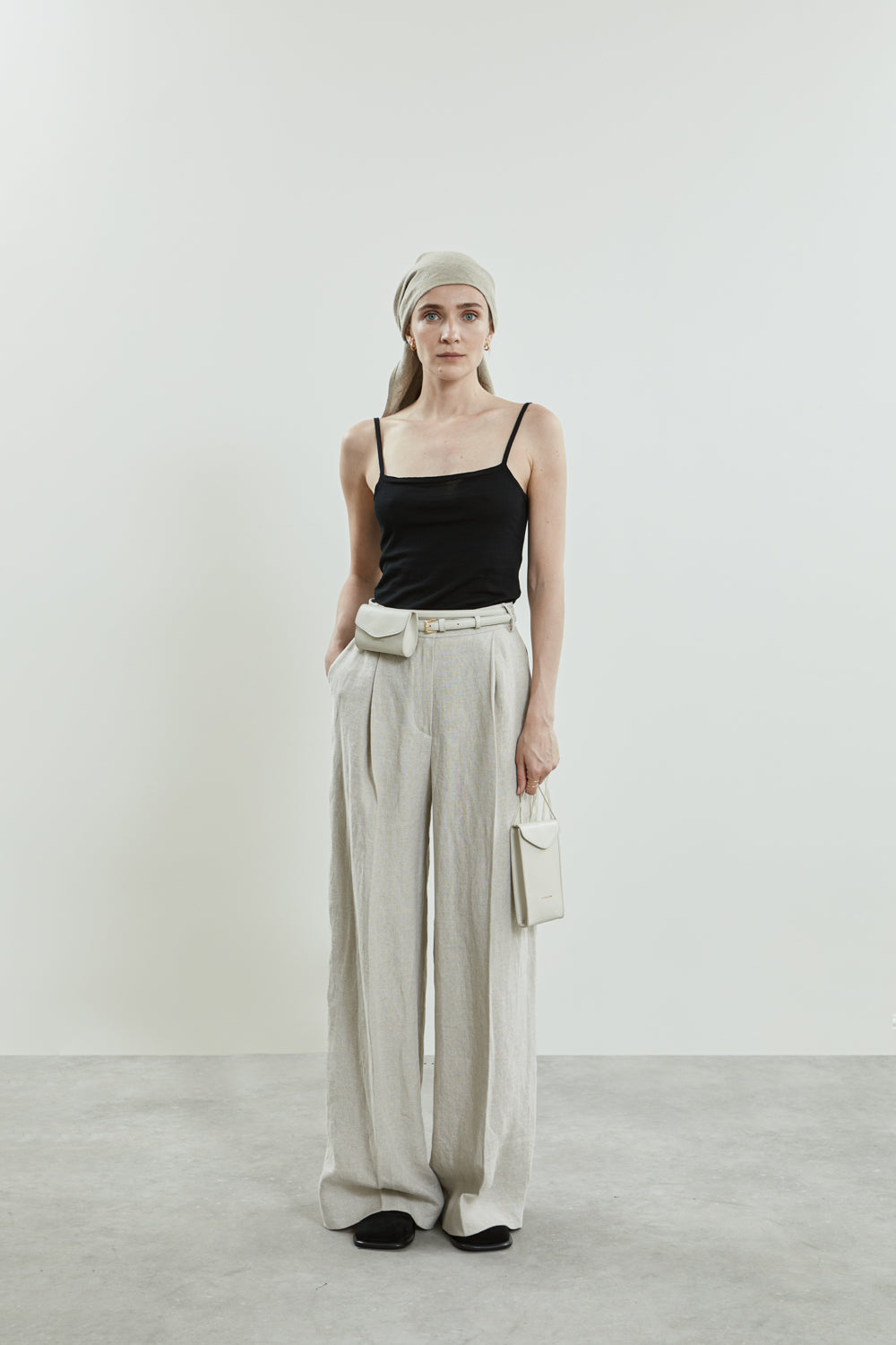 Front view of the beige Dalida trousers in linen, featuring soft pleats and side pockets.