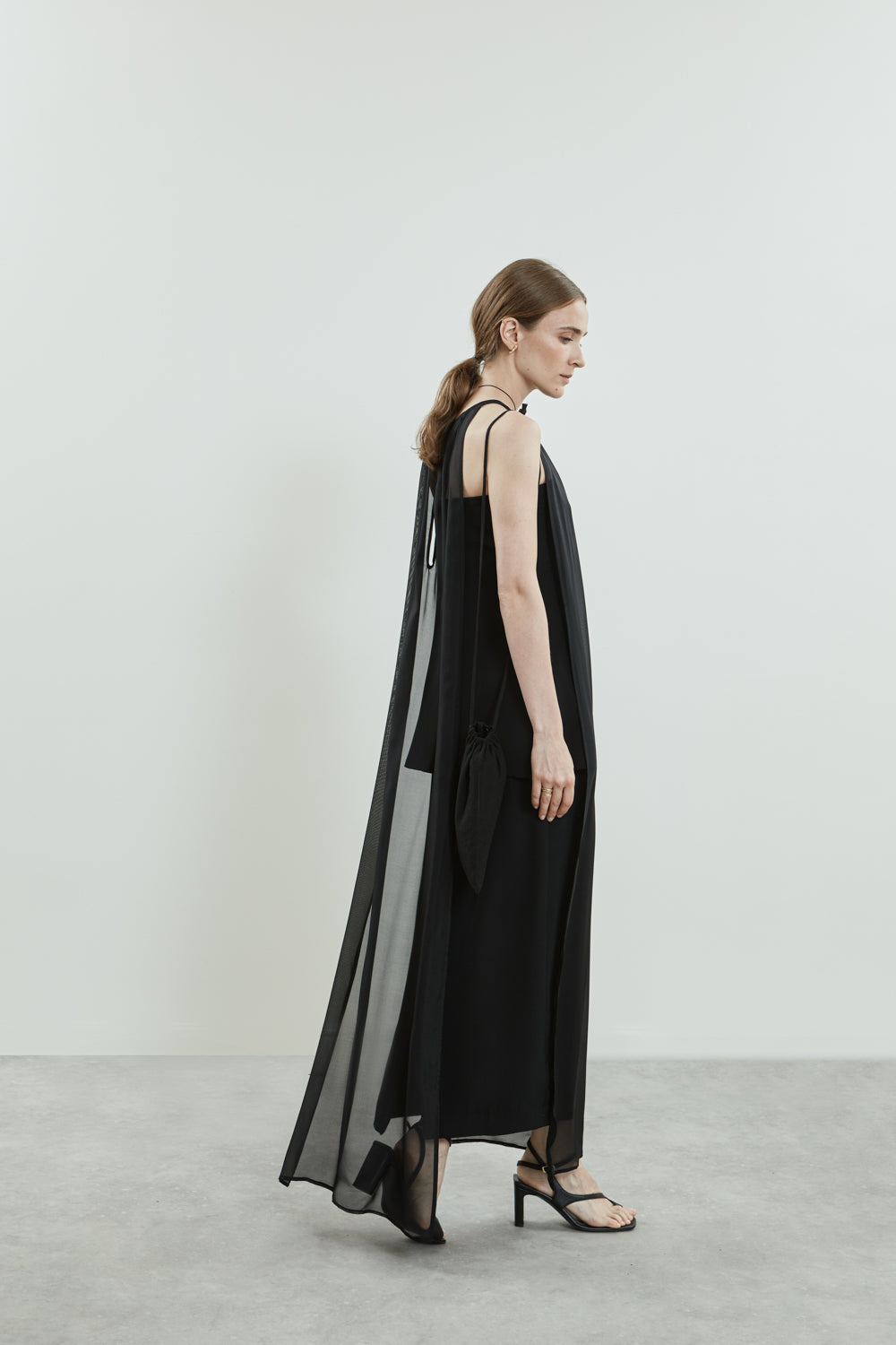 Side view of the black Danni dress, showcasing the open sides and fluid chiffon silk fabric.