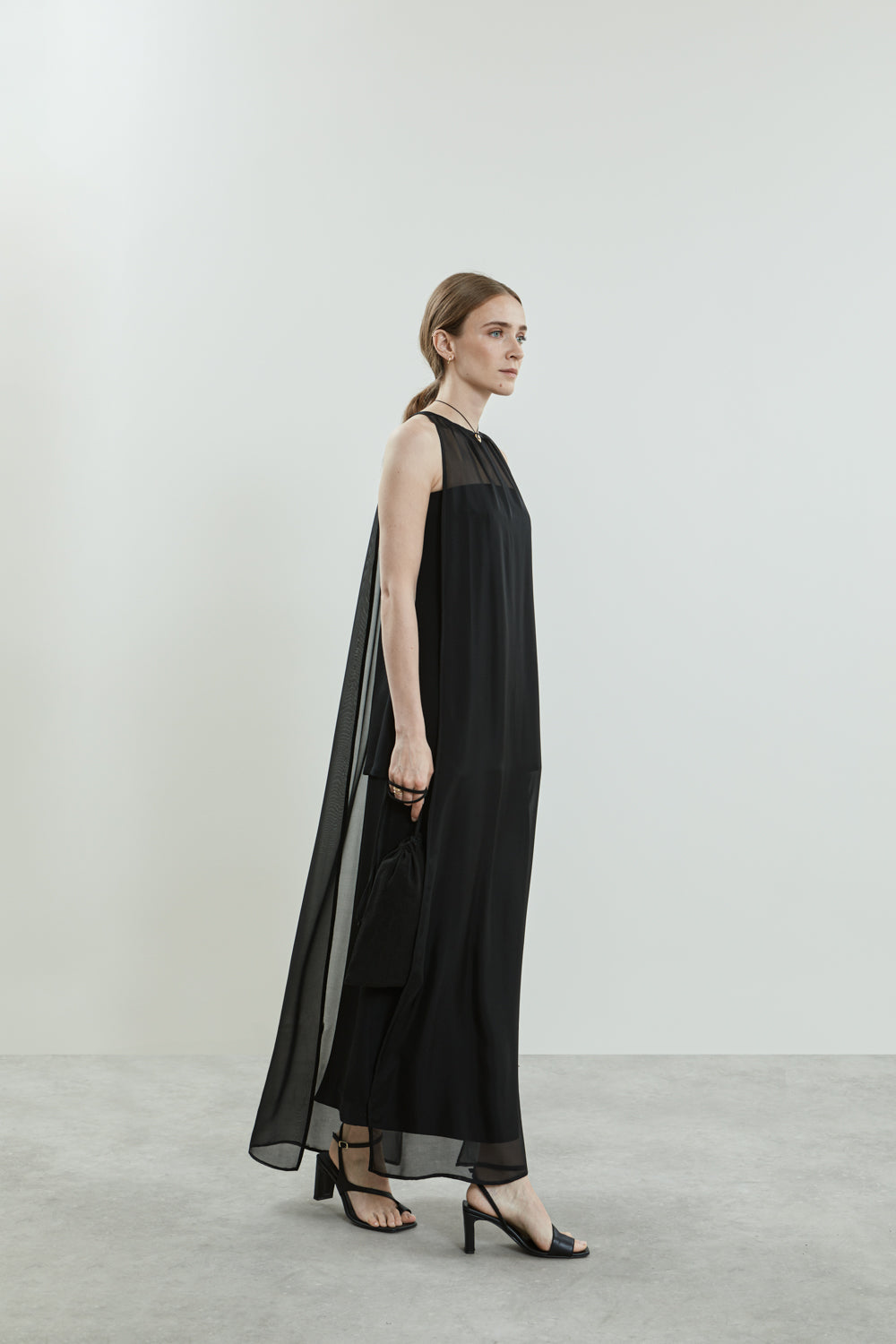 Full-length view of the black Danni dress, featuring open sides and luxurious chiffon silk fabric.