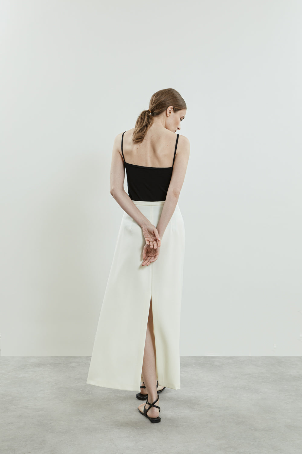 Back view of the off-white Donna skirt in virgin wool, emphasizing the tailored A-line shape and back split.