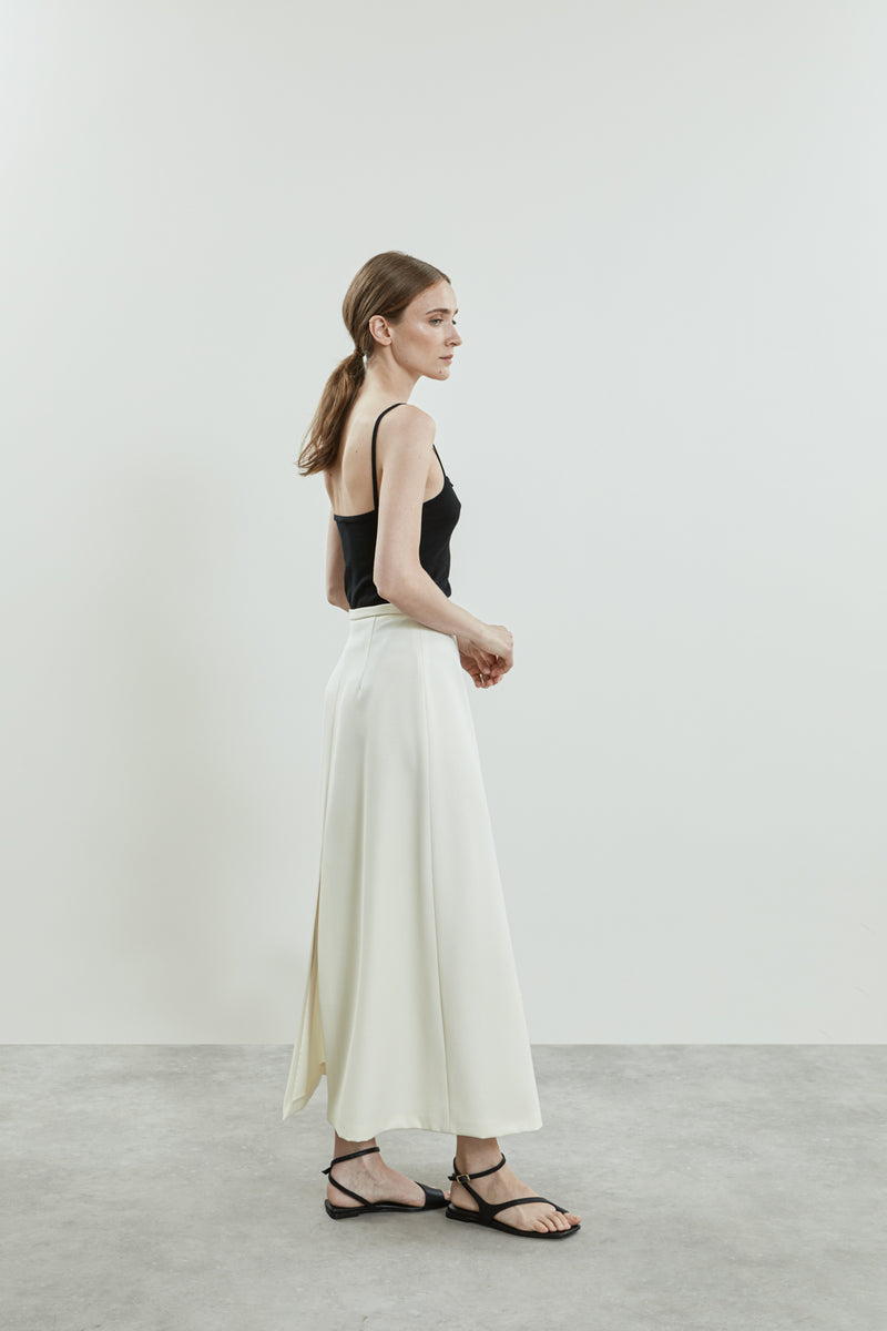 Side view of the off-white Donna skirt, showcasing the flattering A-line silhouette, with sleek splits at the front and back.