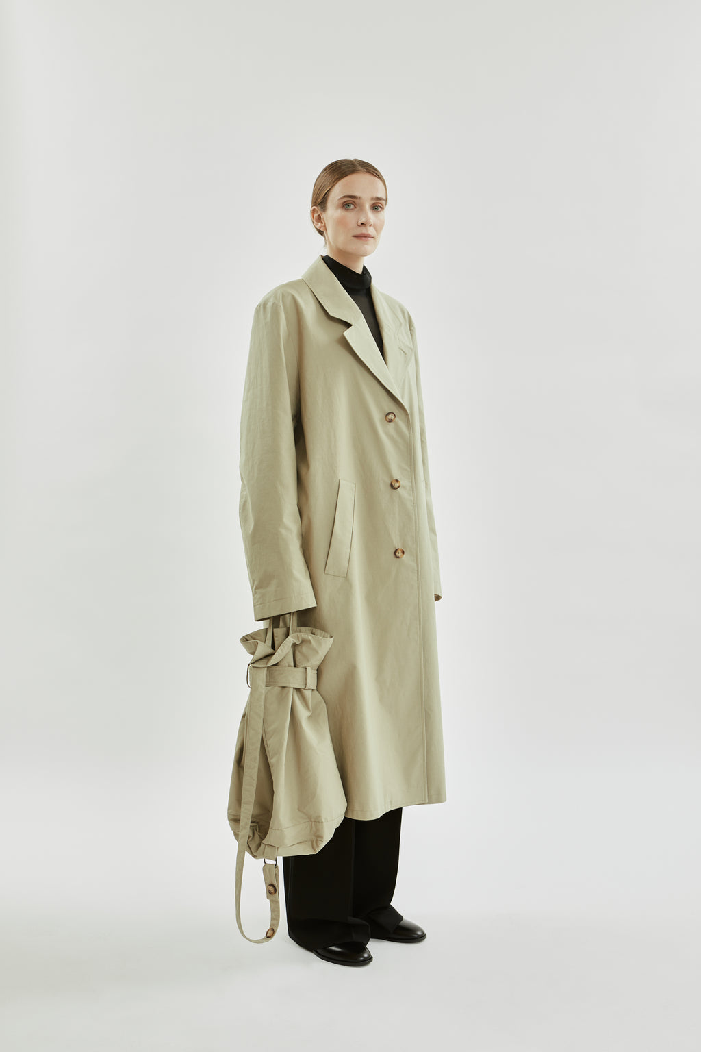 Person wearing a beige trench coat on a white background