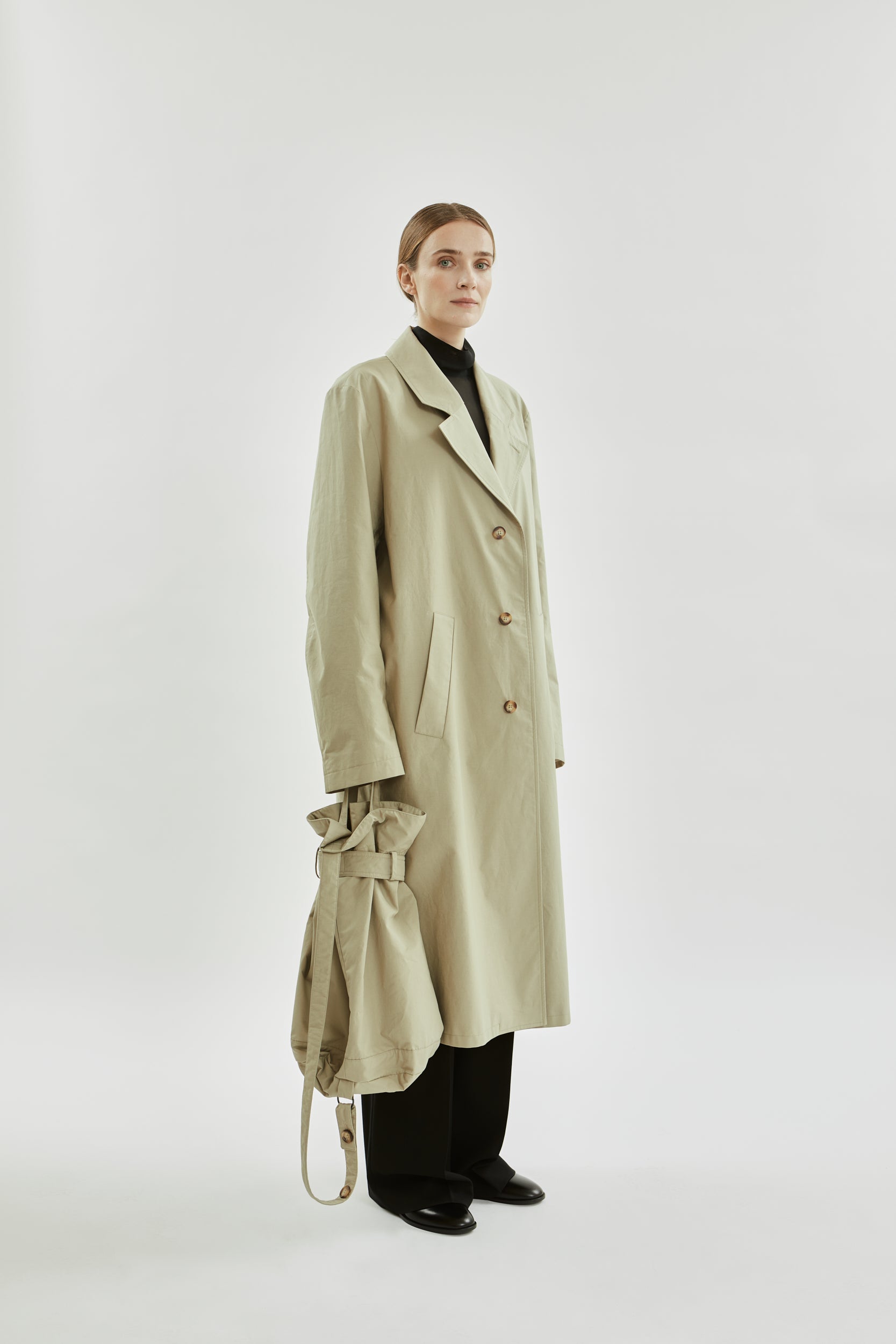 Person wearing a beige trench coat on a white background