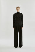 Person wearing a black turtleneck and wide-leg pants on a white background