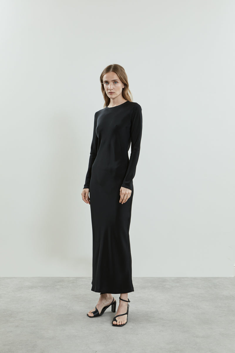 Side view of the black Jacqueline dress in crepe silk, showcasing the fluid, sleek silhouette, high neckline, and long sleeves.