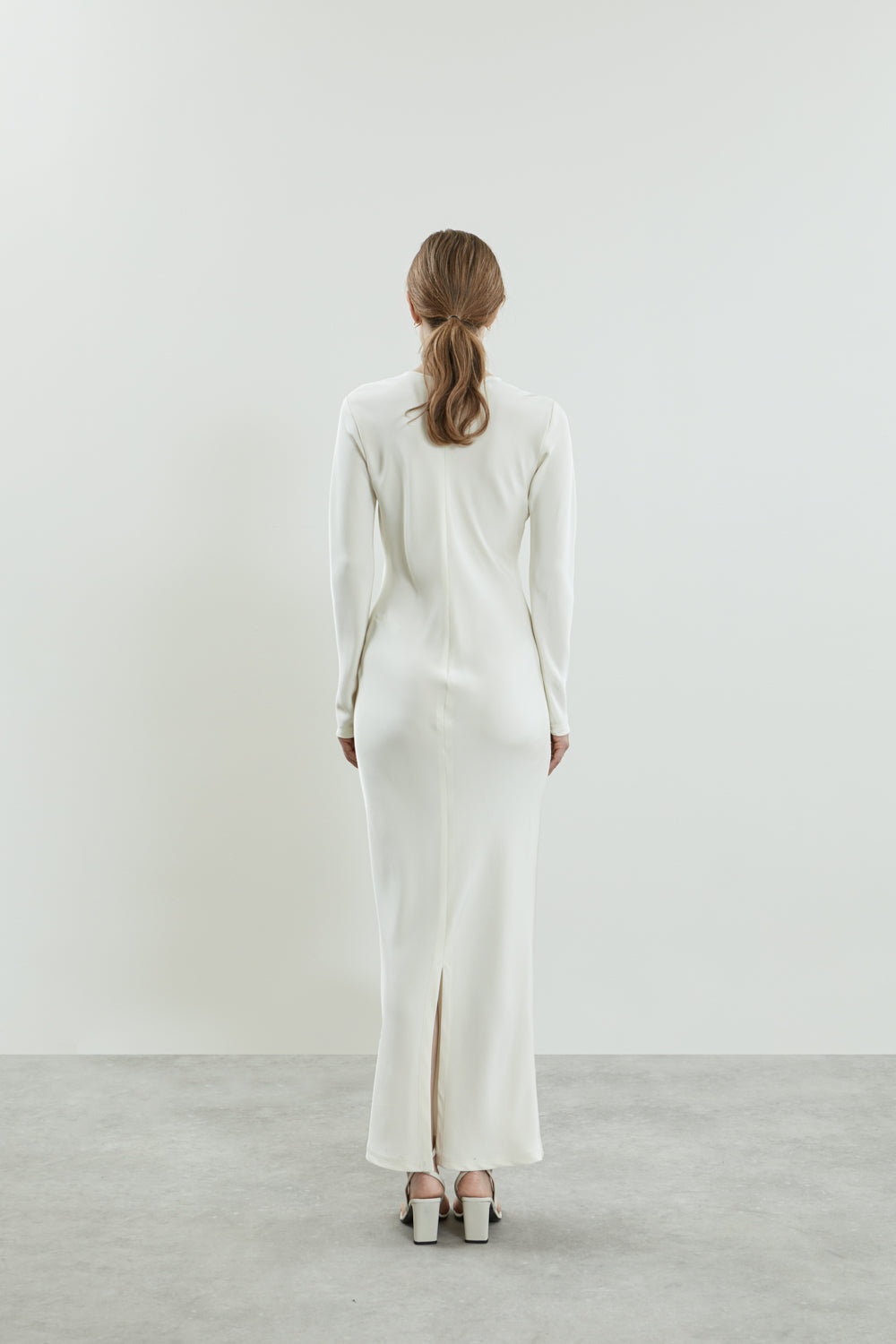 Back view of the off-white Jacqueline dress, highlighting the discreet back slit and elegant long sleeves, crafted from fluid crepe silk.