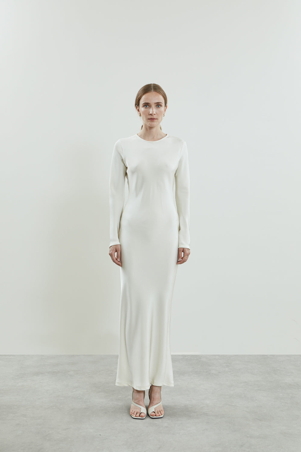 Front view of the off-white Jacqueline dress in fluid crepe silk, featuring a sleek silhouette, high neckline, long sleeves, and back slit.