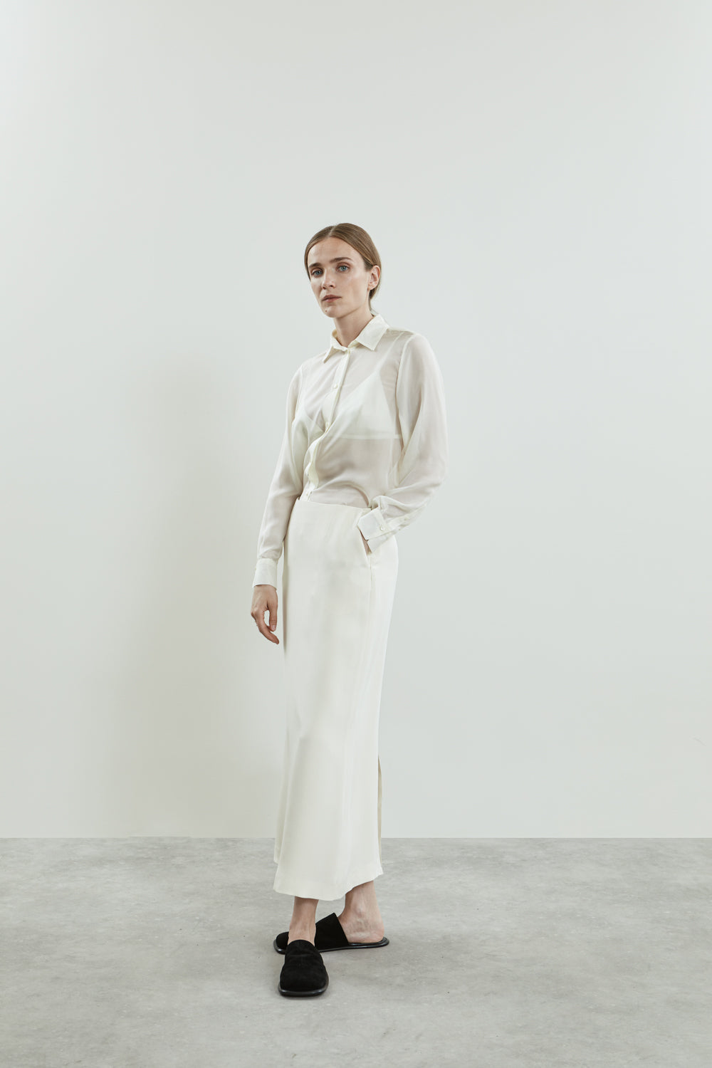 Side view of the off-white Jeannine blouse in chiffon silk, showcasing its fluid silhouette, structured collar, and delicate button details.