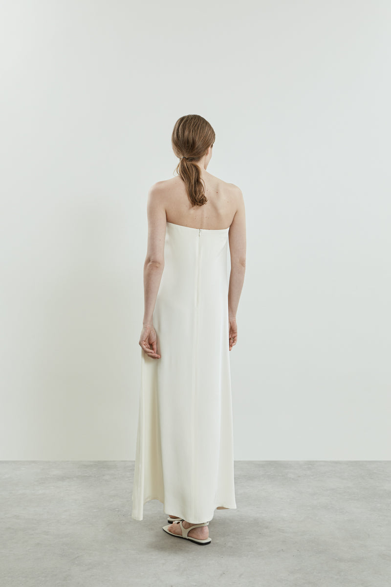 Back view of the off white Joan dress, highlighting the open shoulder design and the flowing crepe silk fabric.