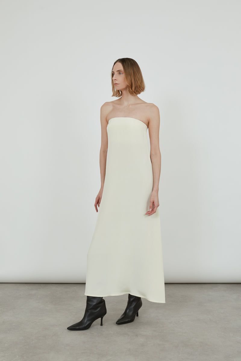 Woman wearing a cream bandeau dress looking sideways.