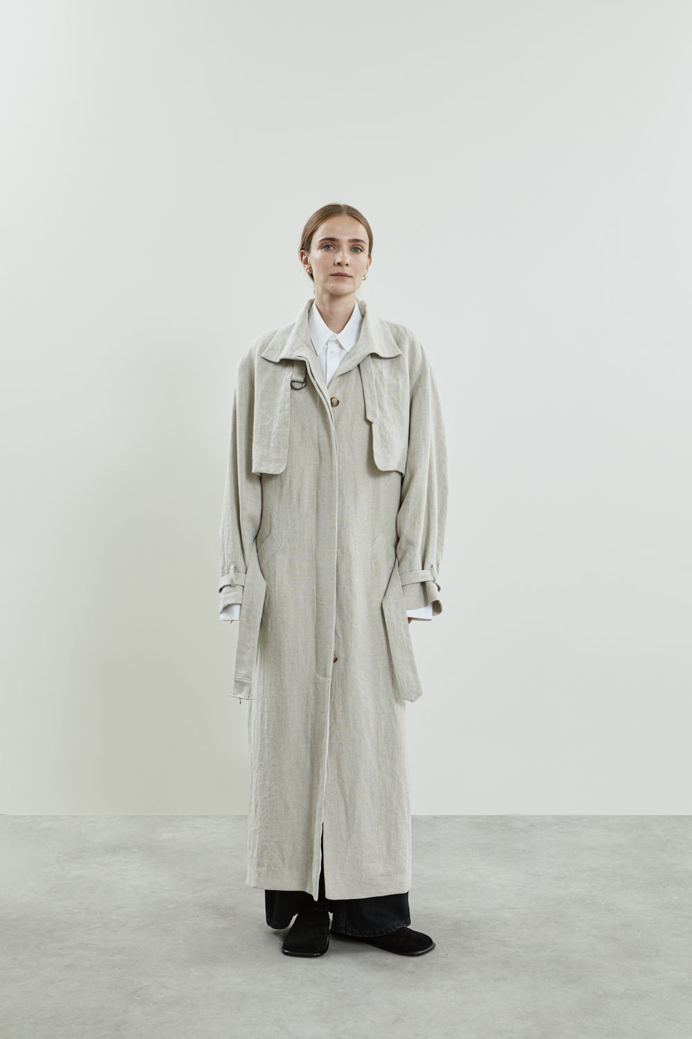 Front view of the beige Jocasta coat in linen, featuring a longline design, high collar, and adjustable belt.