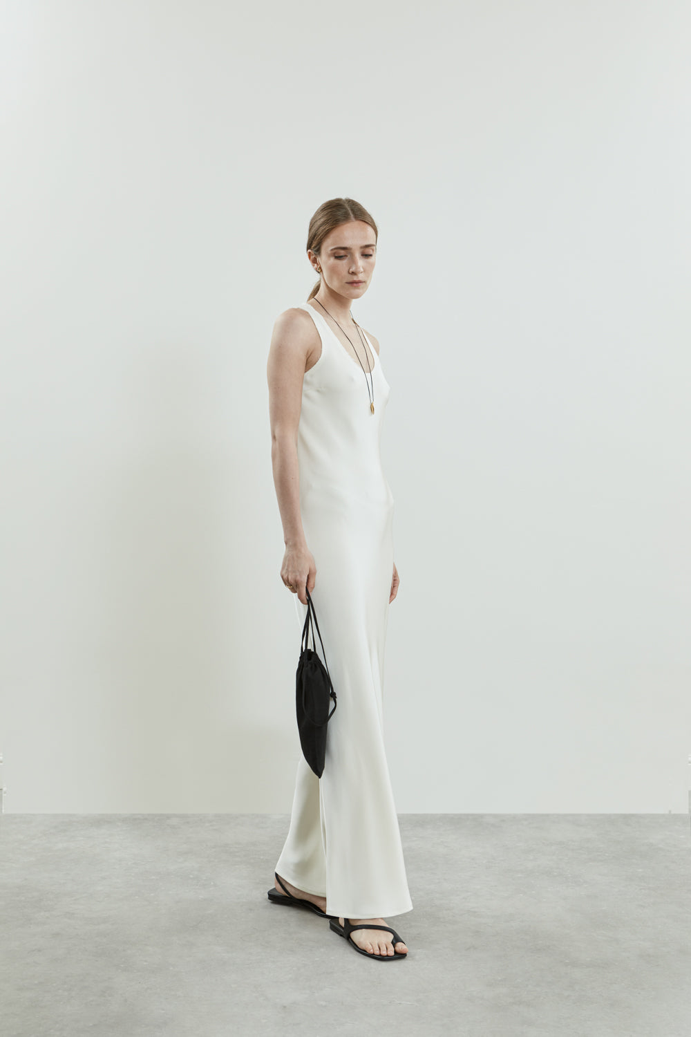 Side view of the off-white Kate dress in crepe silk, showcasing the sleek, form-fitting silhouette, clean scooped neckline.