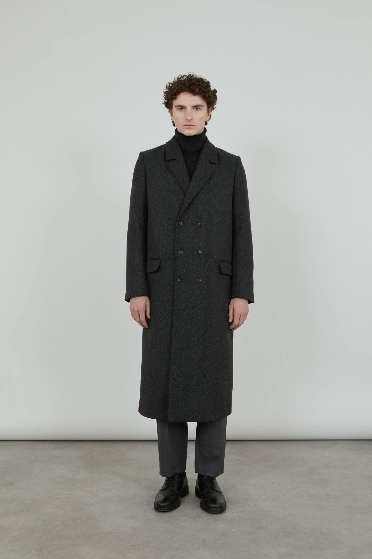 A man wearing a dark grey double-breasted coat in a wool blend.