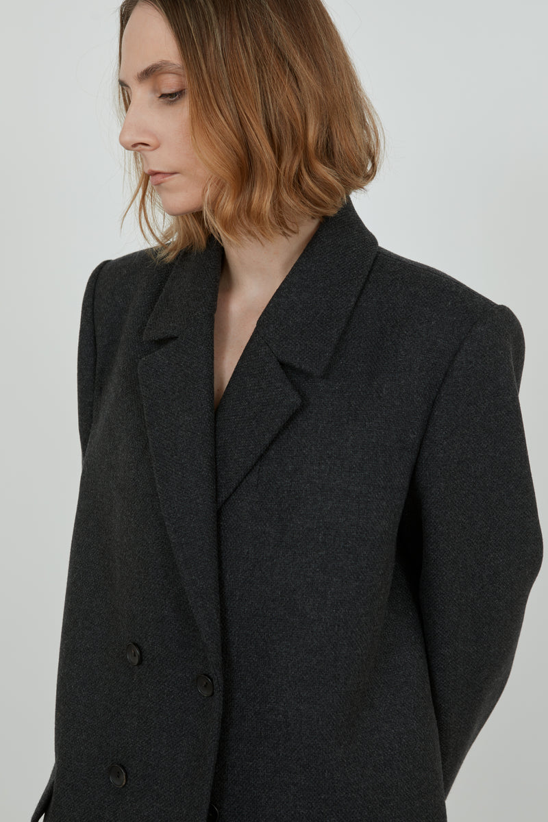 A woman is wearing a dark grey wool blend overcoat and we get a detailed view of the coat.