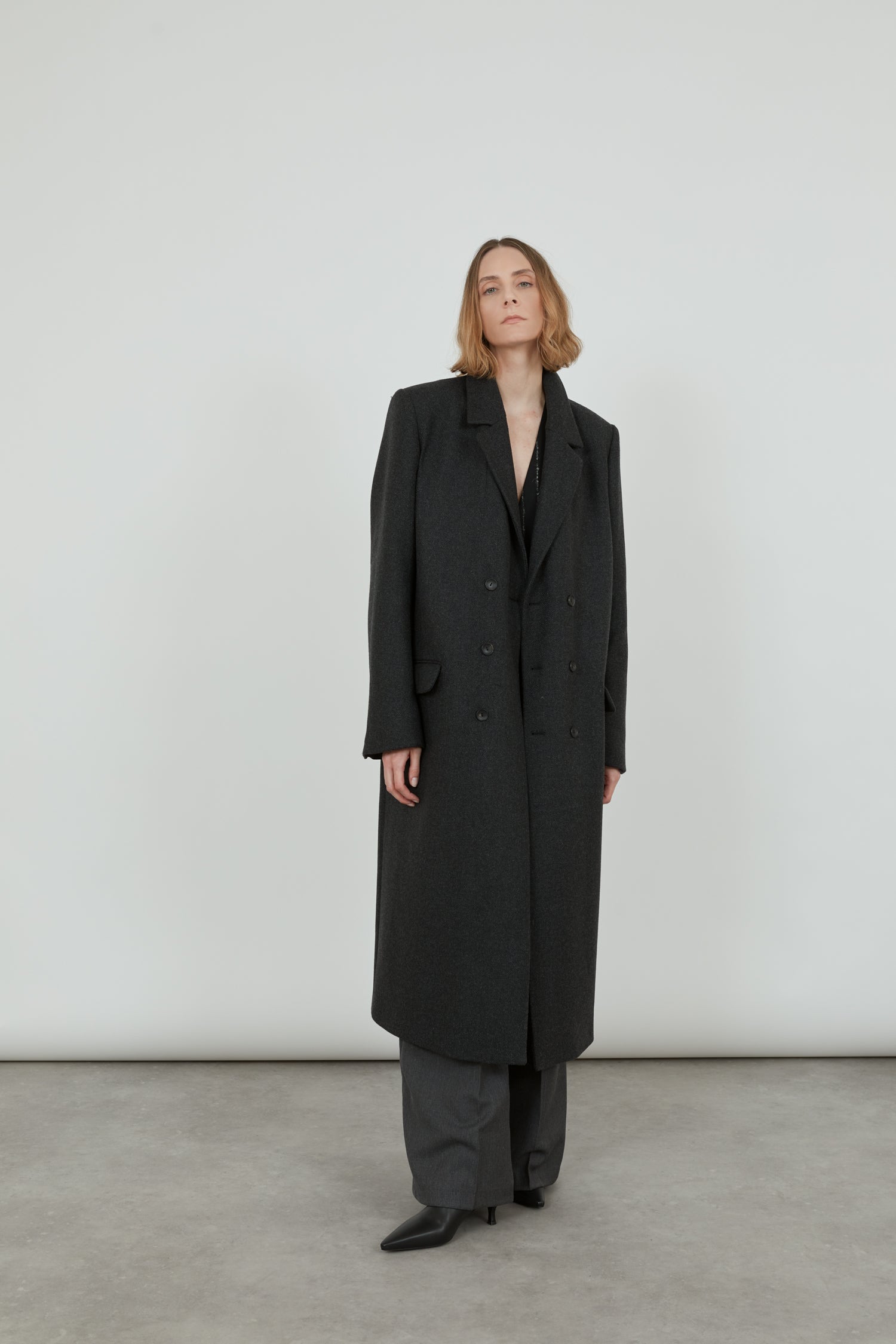 A woman wearing a double-breasted, wool blend coat. The coat is open.