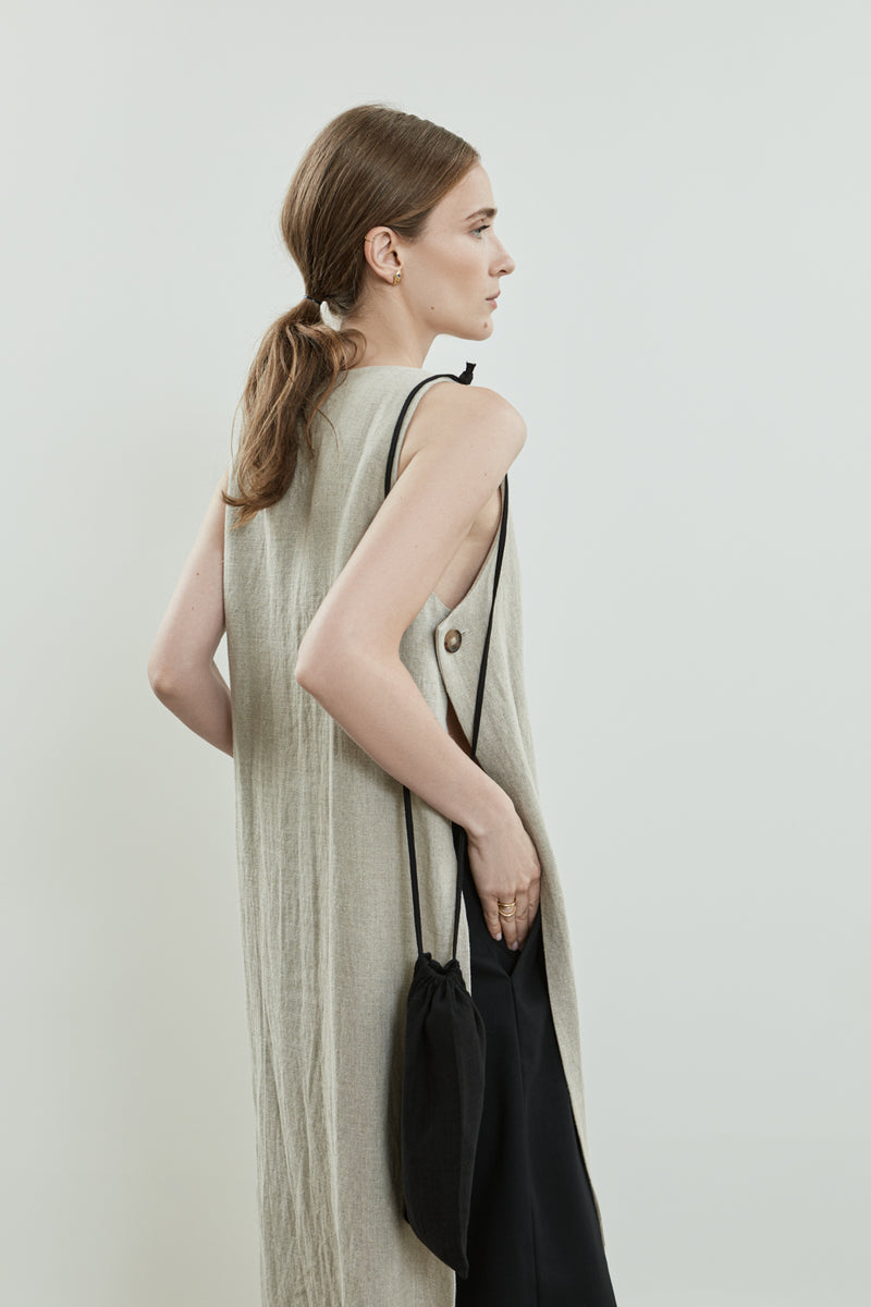 Back view of the beige Louise dress in linen, highlighting the sleeveless design and the clean lines of the dress.