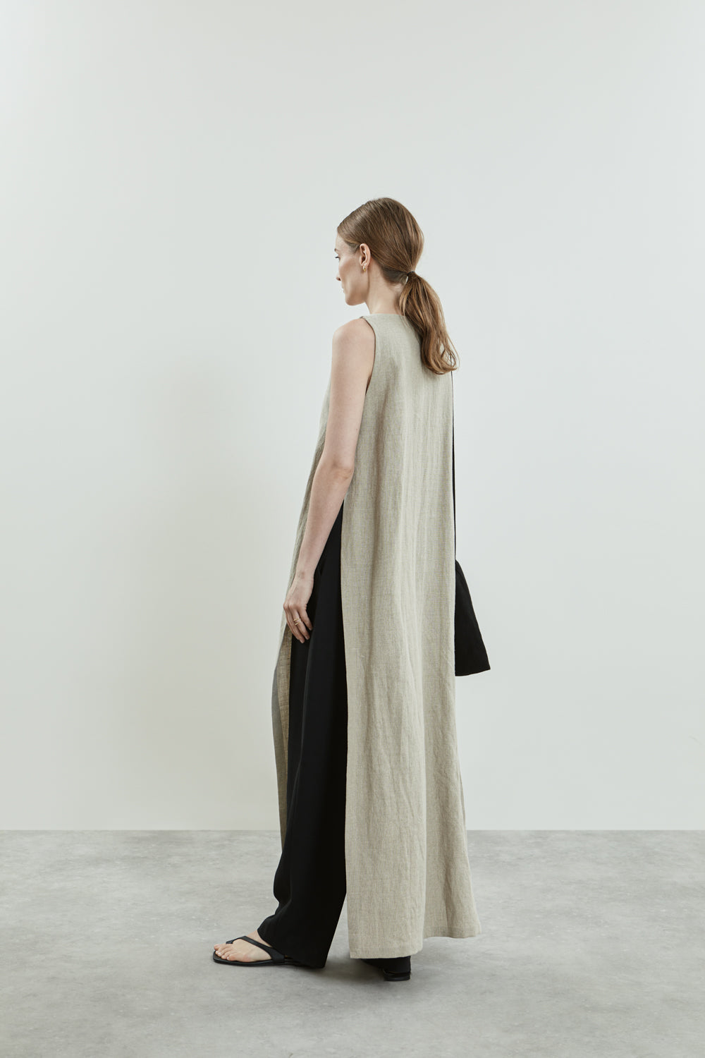 Side view of the beige Louise dress in linen, showcasing the relaxed silhouette and sleeveless design.