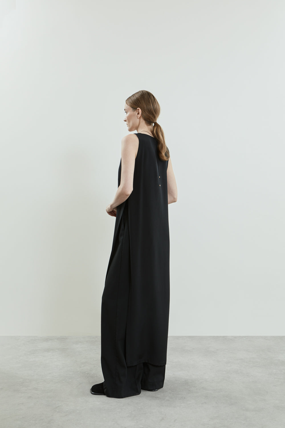 Side view of the black Louise dress in crepe silk, showcasing the relaxed silhouette and sleeveless design.