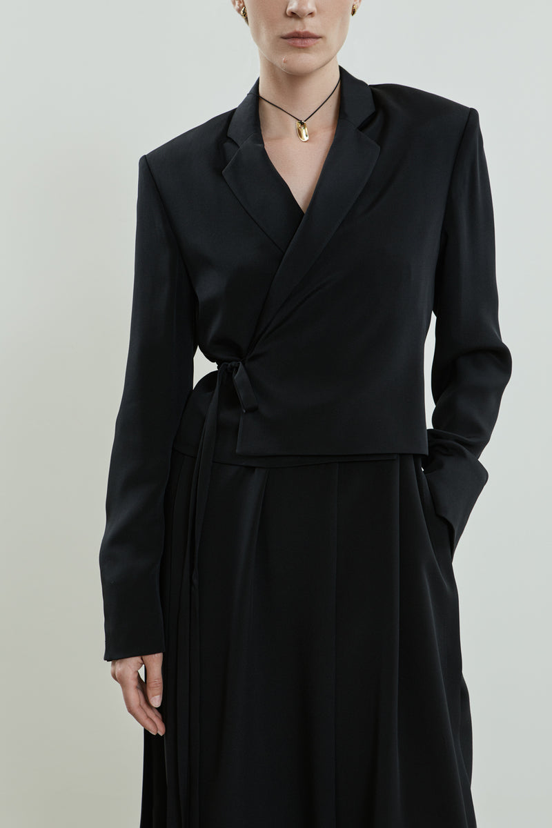 Close-up of the Lynn blazer in black crepe silk, showing the wrap-style waist tie, sharp notched lapels.