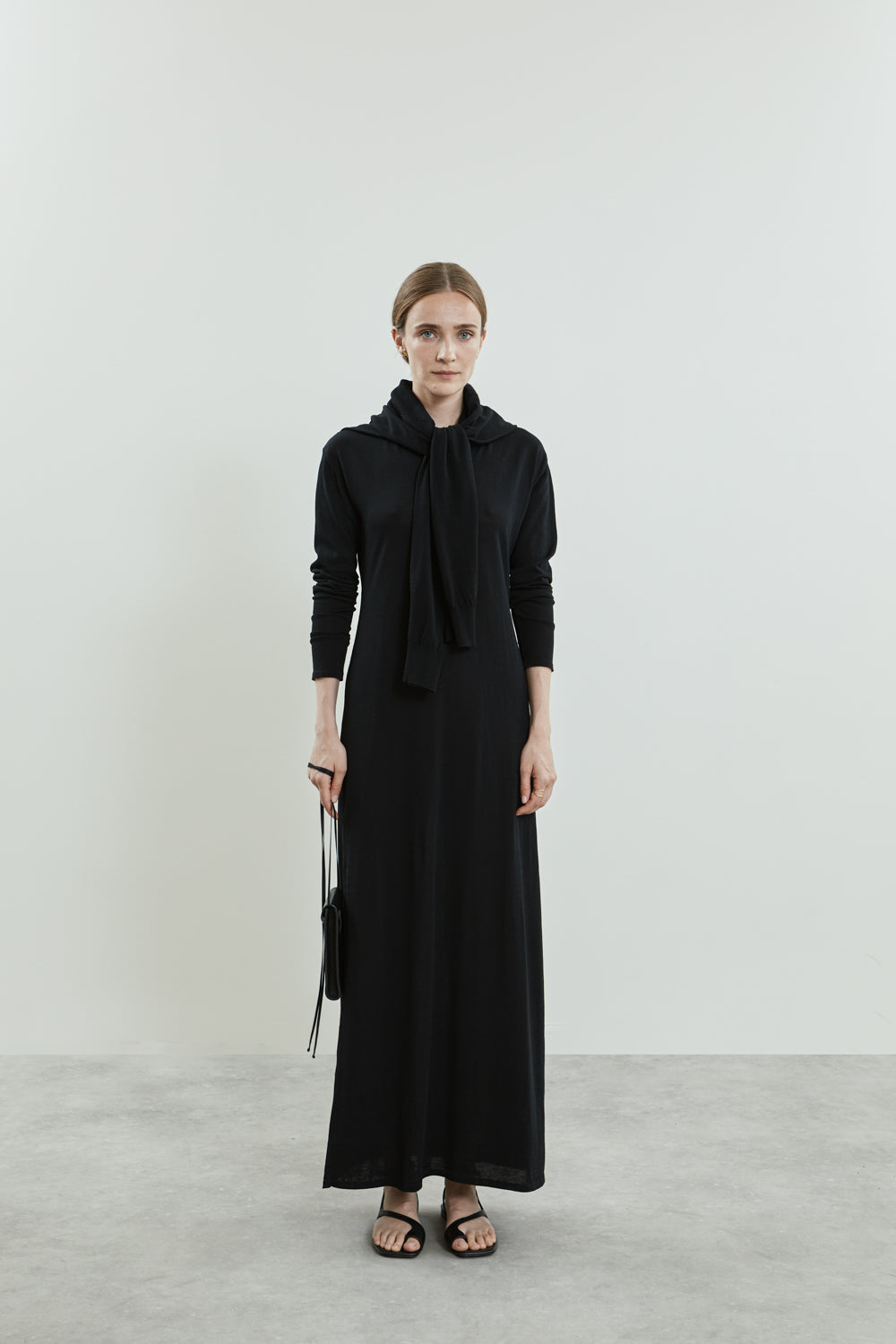 Front view of the Olive knitted dress in black cotton knit, featuring a maxi length, ribbed cuffs, and a round neckline.