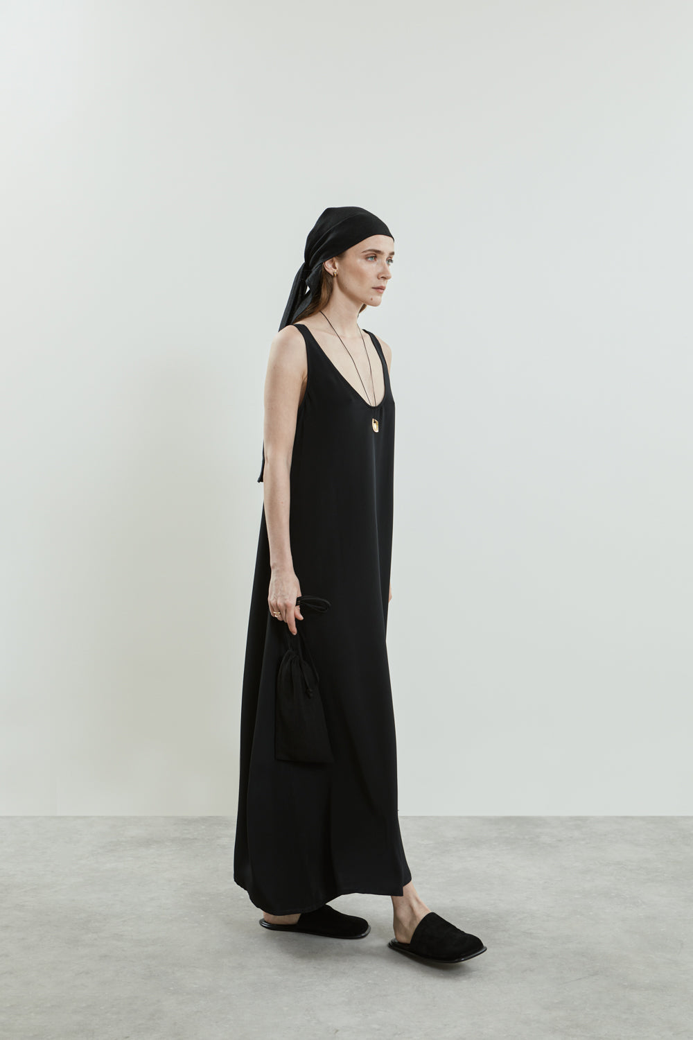 Side view of the Quinn dress in black crepe silk, showcasing its fluid A-line shape and floor-length drape.