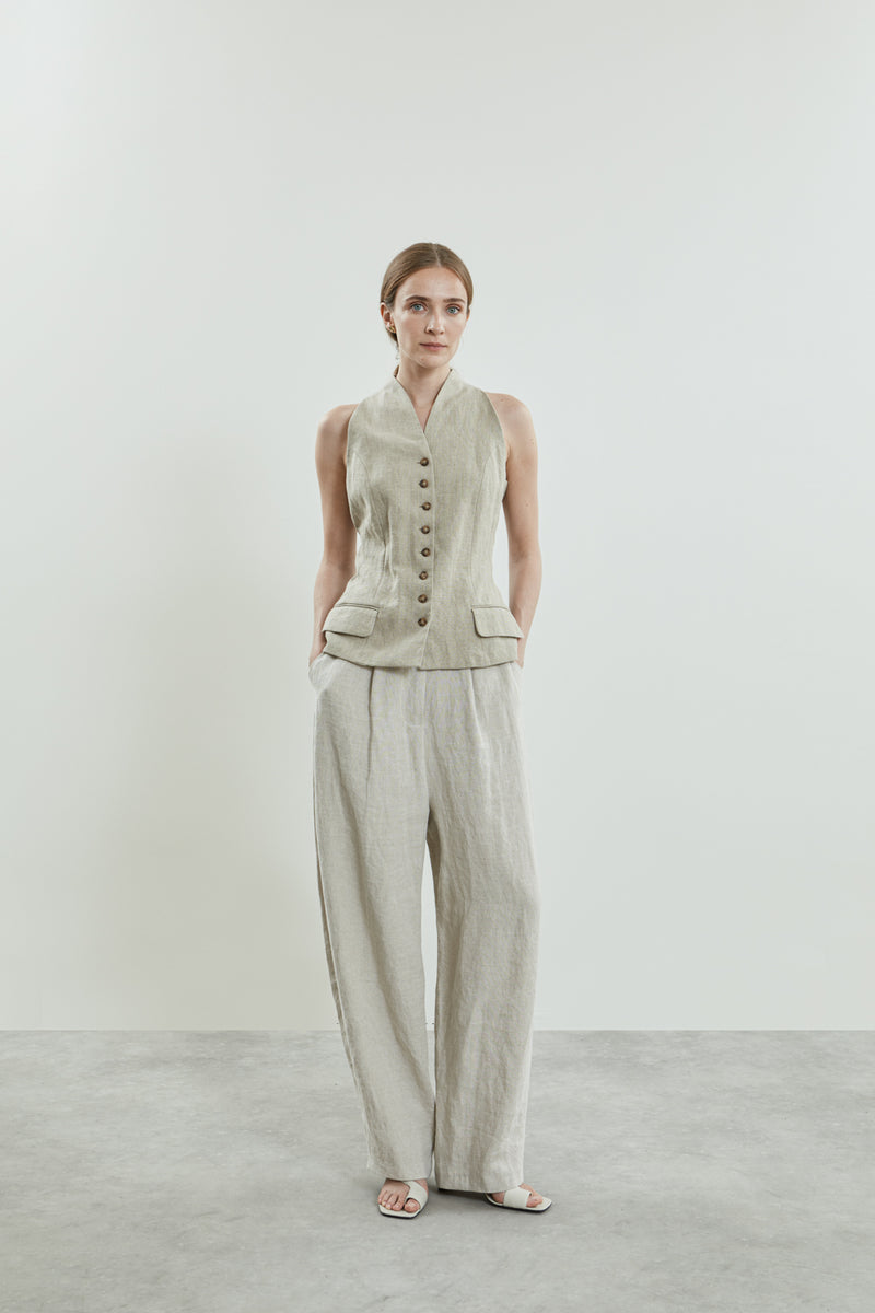 Front view of the Sada trousers in beige linen, featuring a slightly dropped crotch, side pockets, and belt loops.