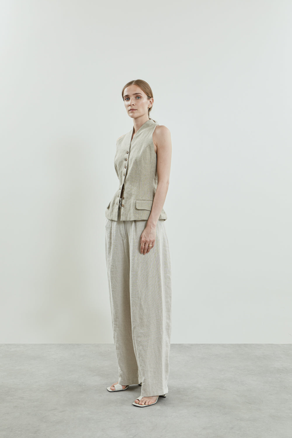 Side view of the Sada trousers in beige linen, featuring a slightly dropped crotch and side pockets.