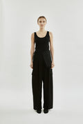 Person wearing a black sleeveless top and wide-leg pants on a white background
