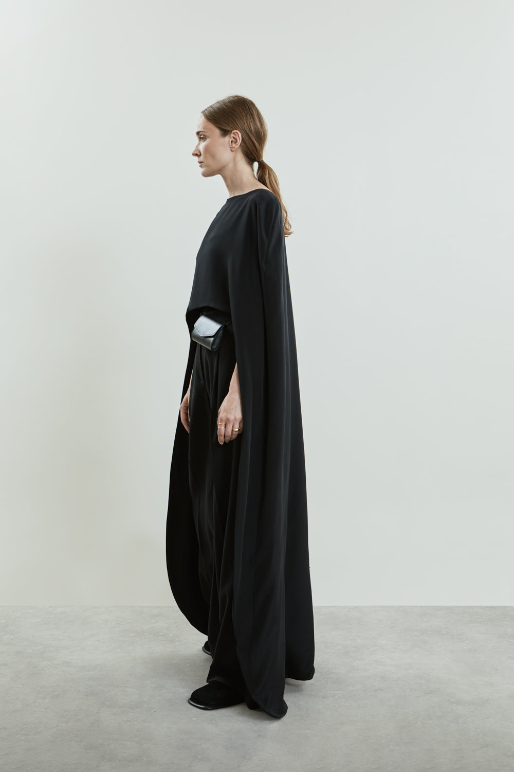 Side view of the Ursula cape in black crepe silk, elegantly draping over the shoulders with fluid movement.