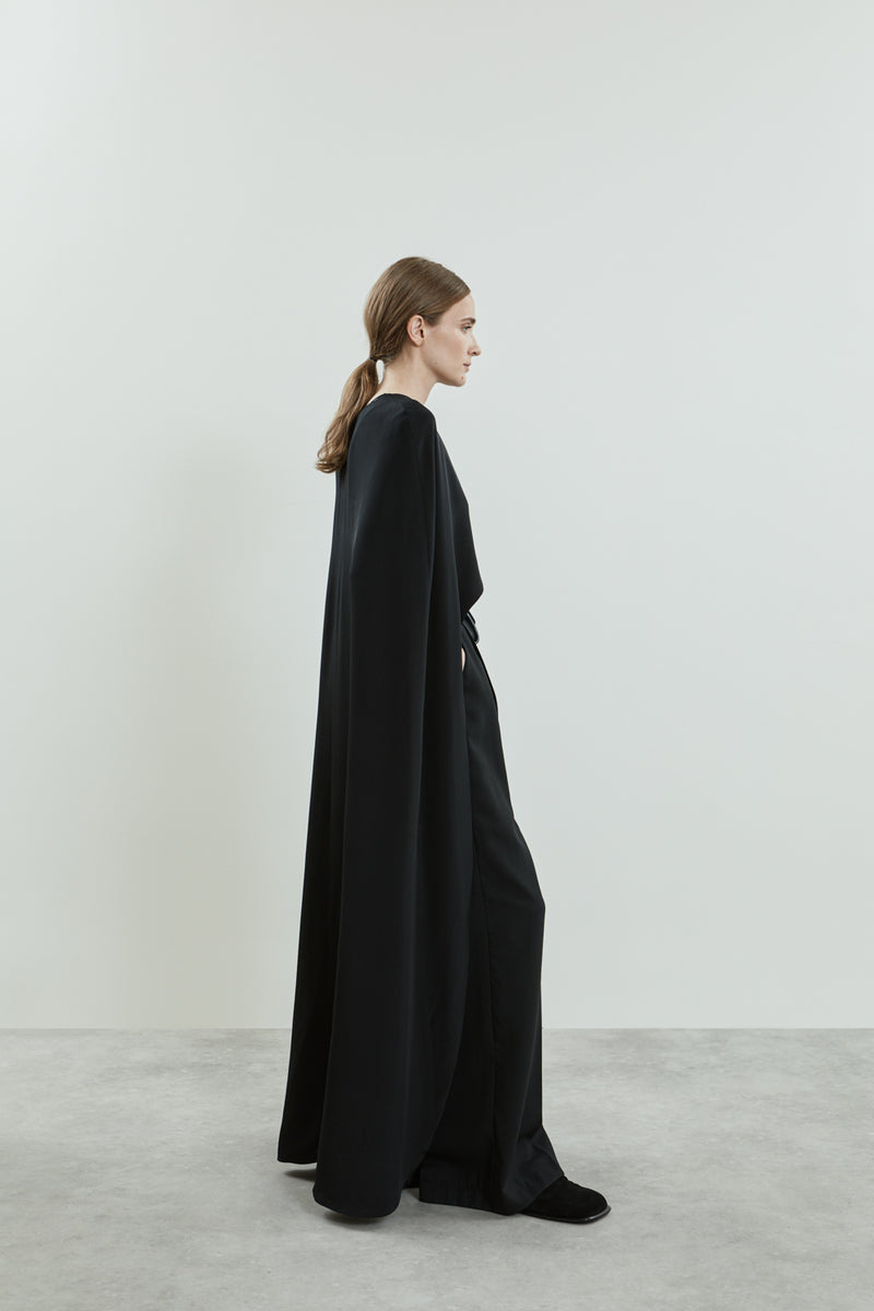 Side view of the Ursula cape in black crepe silk, elegantly draping over the shoulders with fluid movement.