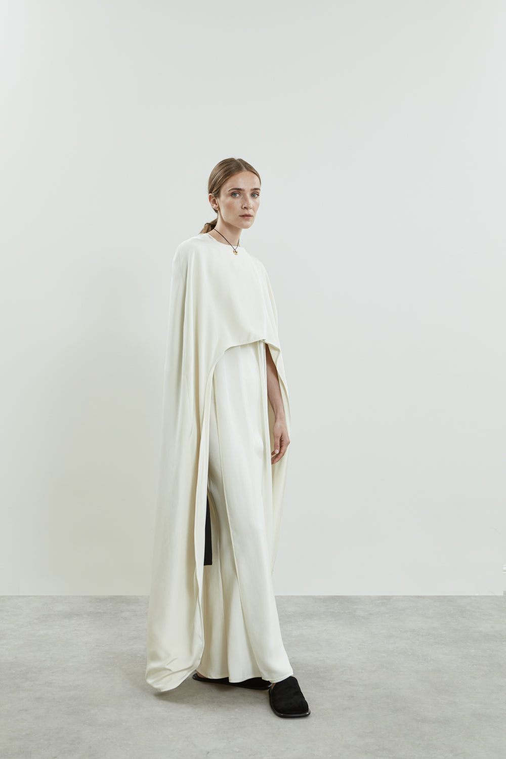 Side view of the Ursula cape in off white crepe silk.