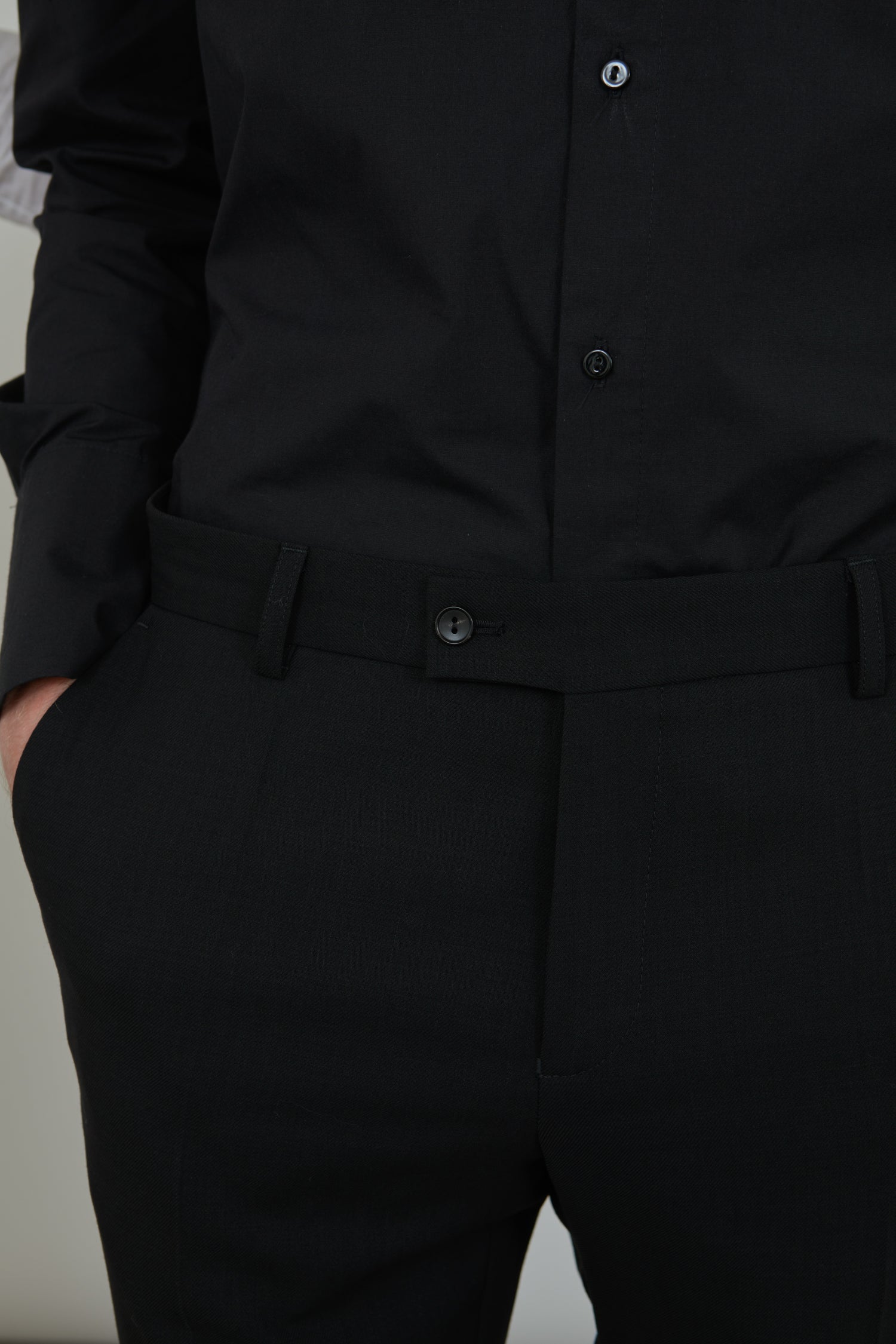 Man wearing a classic black trousers in virgin wool, combined with a classic black shirt, detailed view.